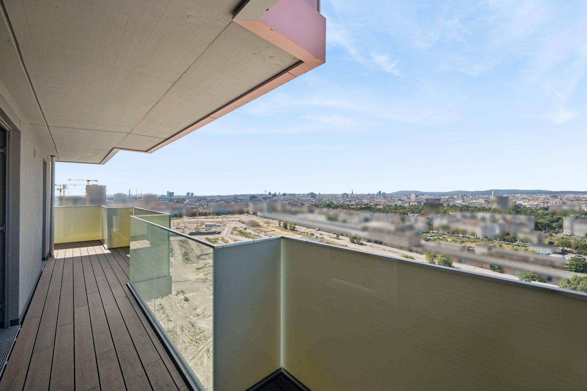 Langer Balkon mit Glasgeländer und weitem Blick über die Stadtlandschaft.