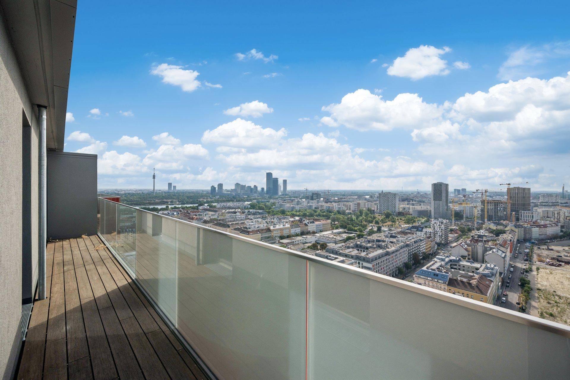 Geräumiger Balkon mit Holzbelag und beeindruckendem Panoramablick über die Stadt.