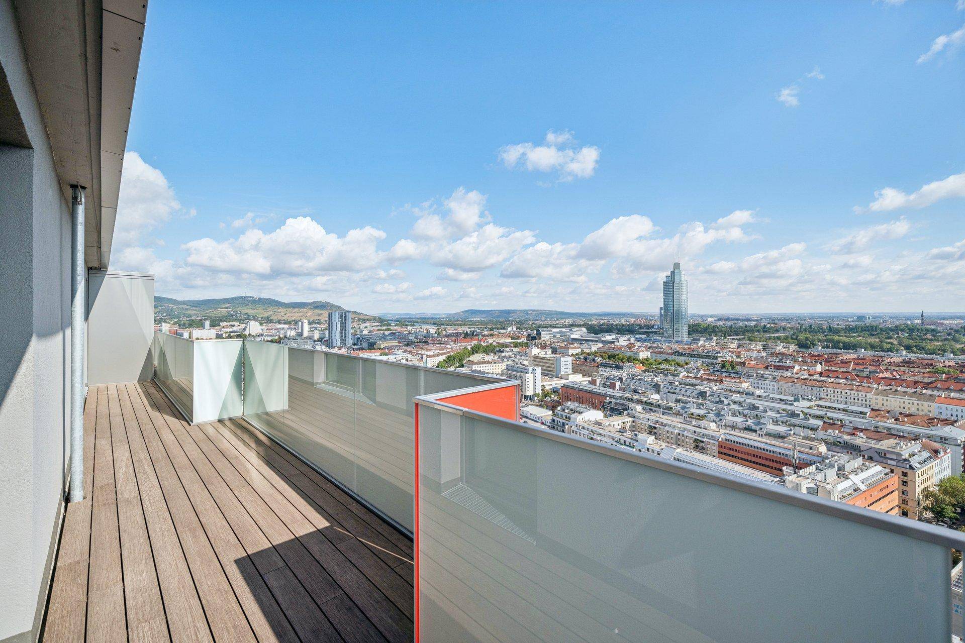 Geräumiger Balkon mit Holzboden und weitem Blick über die Stadt und die umliegenden Hügel.