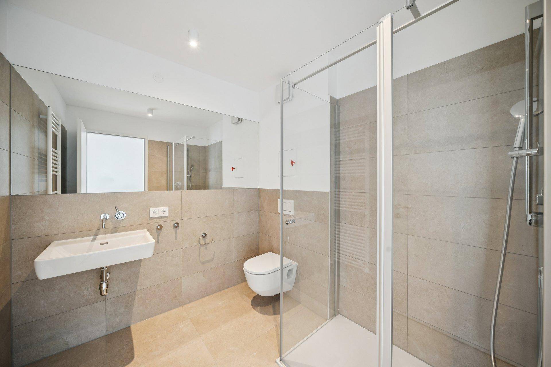 Modernes Badezimmer mit begehbarer Dusche, Wand-WC und großem Spiegel.