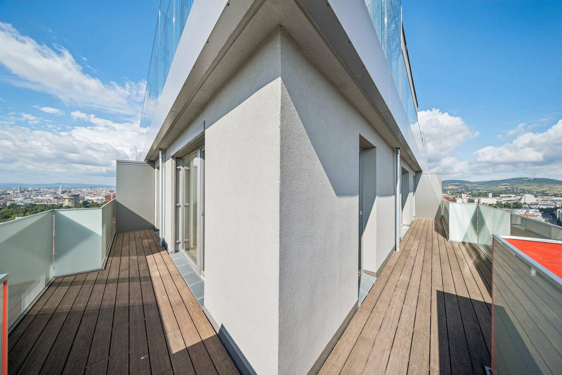 Eckbalkon mit Holzboden und Glasgeländer, bietet weite Ausblicke auf die Umgebung.