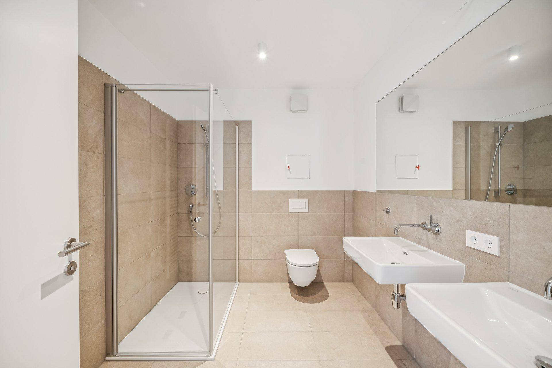 Modernes Badezimmer mit begehbarer Dusche, Doppelwaschbecken und beigefarbenen Fliesen.