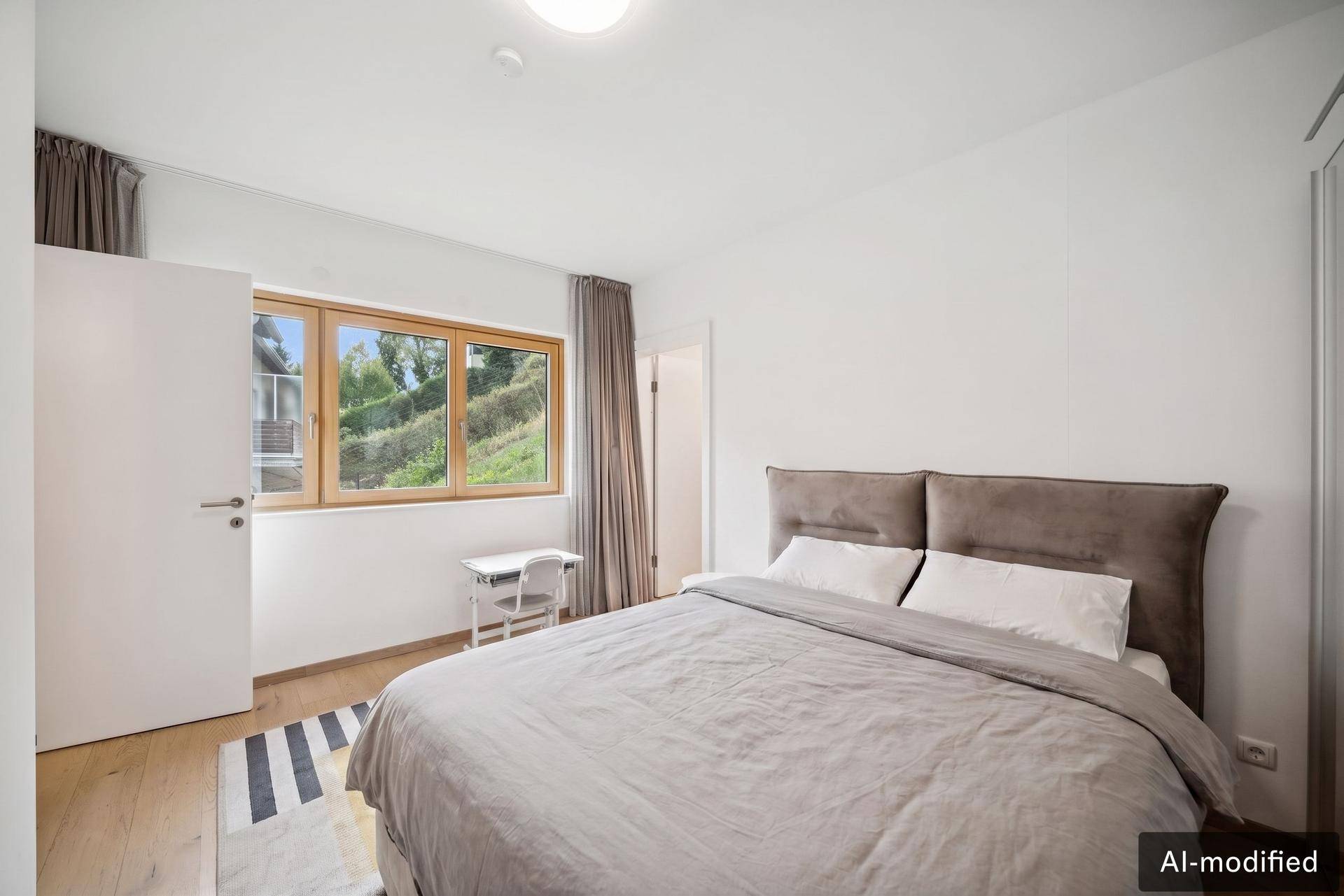 Helles Schlafzimmer mit Holzboden, großem Fenster und einem bequemen Doppelbett, schlicht eingerichtet.