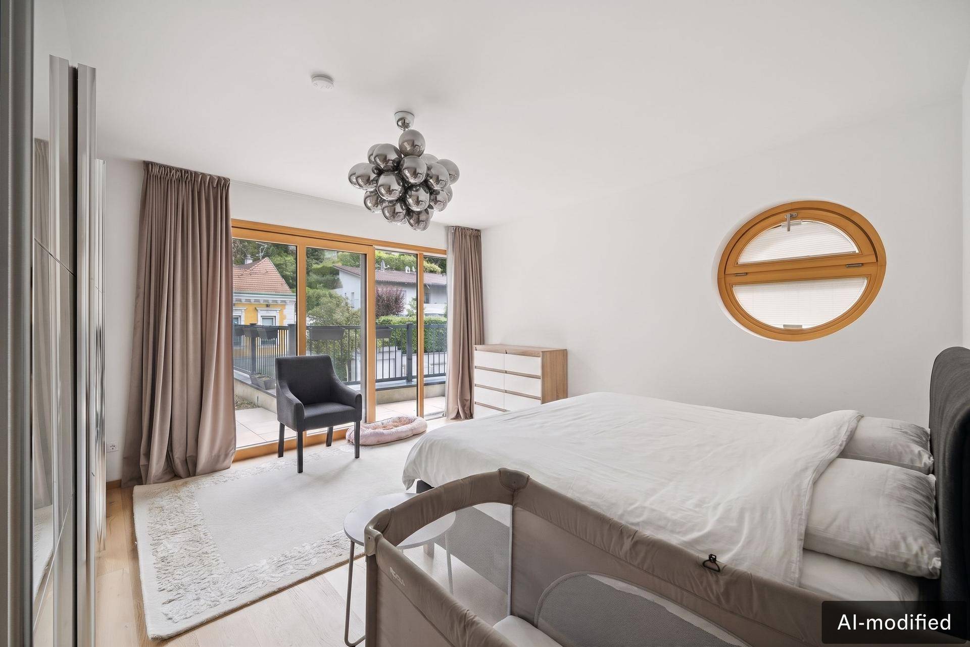 Modernes Schlafzimmer mit Zugang zum Balkon, Holzboden und einem runden Fenster als Akzent.