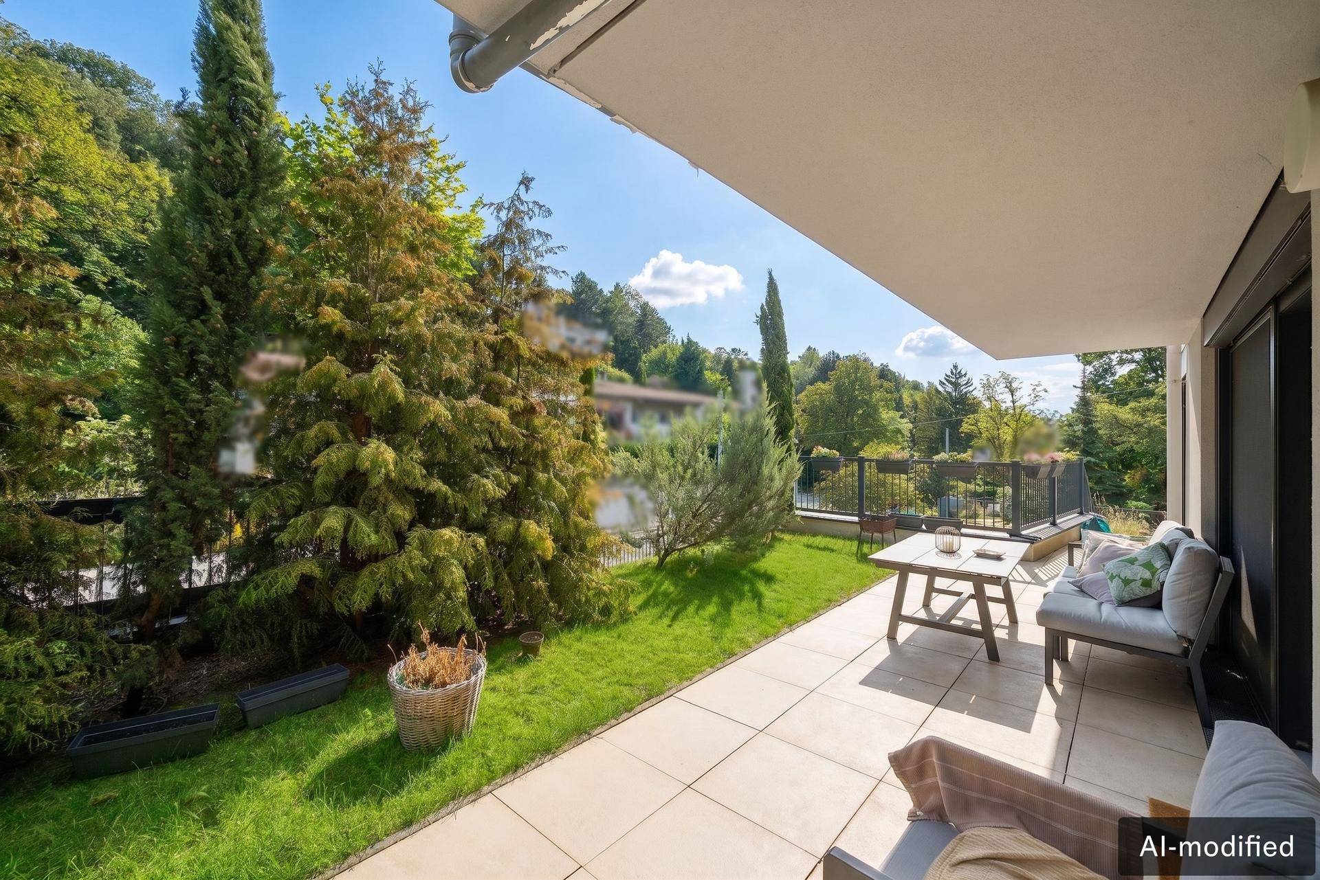 Sonniger Terrassenbereich mit Gartenmöbeln und Blick ins Grüne, umgeben von hohen Bäumen.