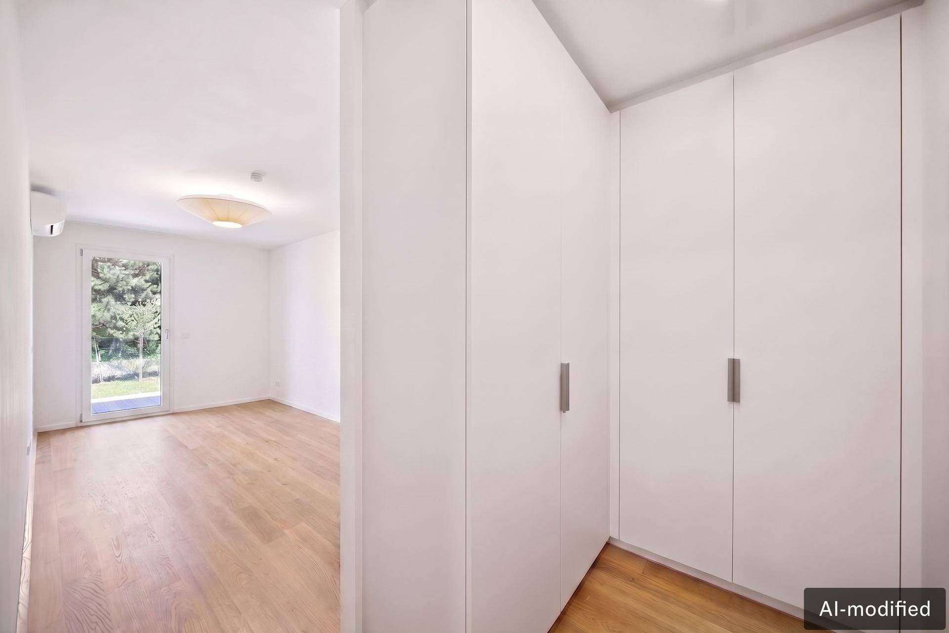 Heller Flur mit Einbauschränken und Zugang zu einem Zimmer mit Balkontür.