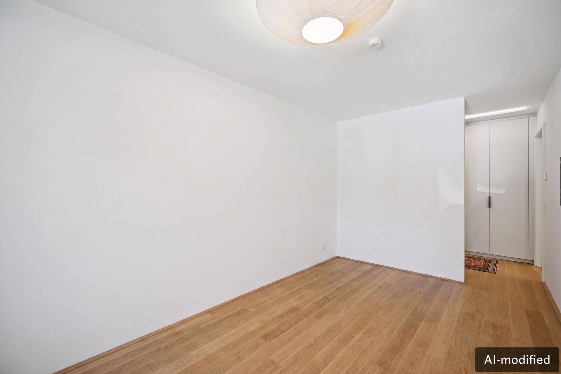 Leeres Zimmer mit hellem Holzboden und moderner Deckenleuchte, bereit zur Einrichtung.