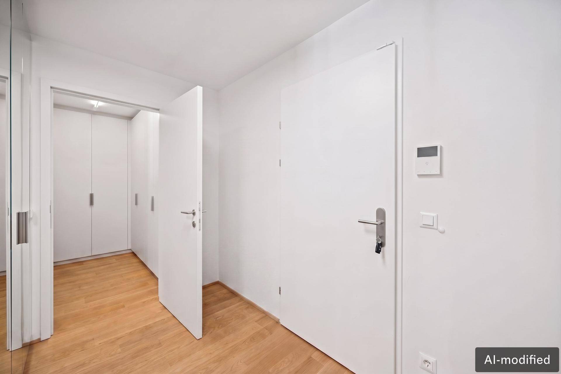 Eingangsbereich mit Holzboden, weißer Tür und integrierten Schränken für Stauraum.