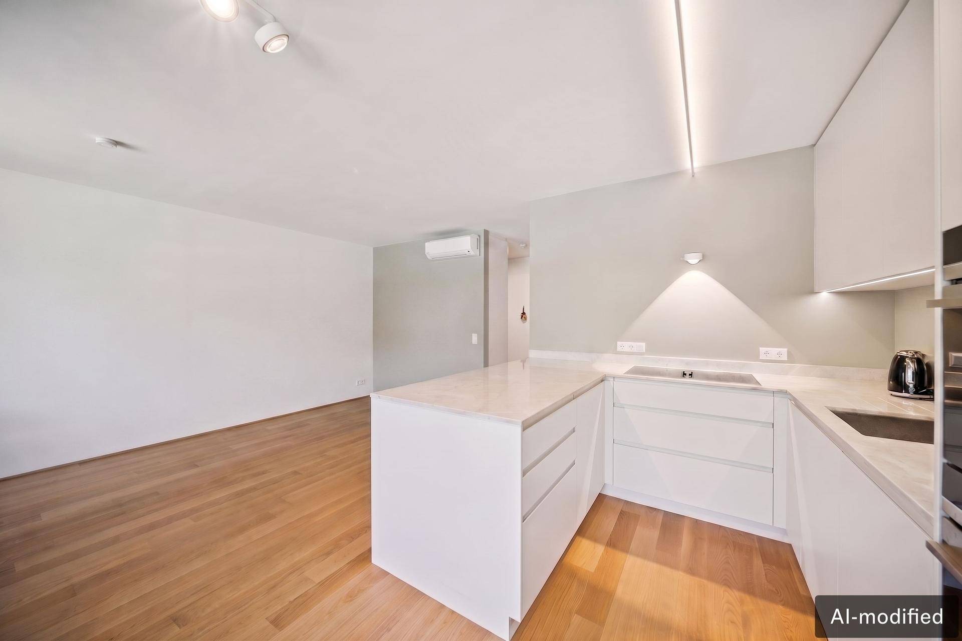 Moderne weiße Einbauküche mit Kochinsel und hellem Holzboden in offenem Wohnbereich.