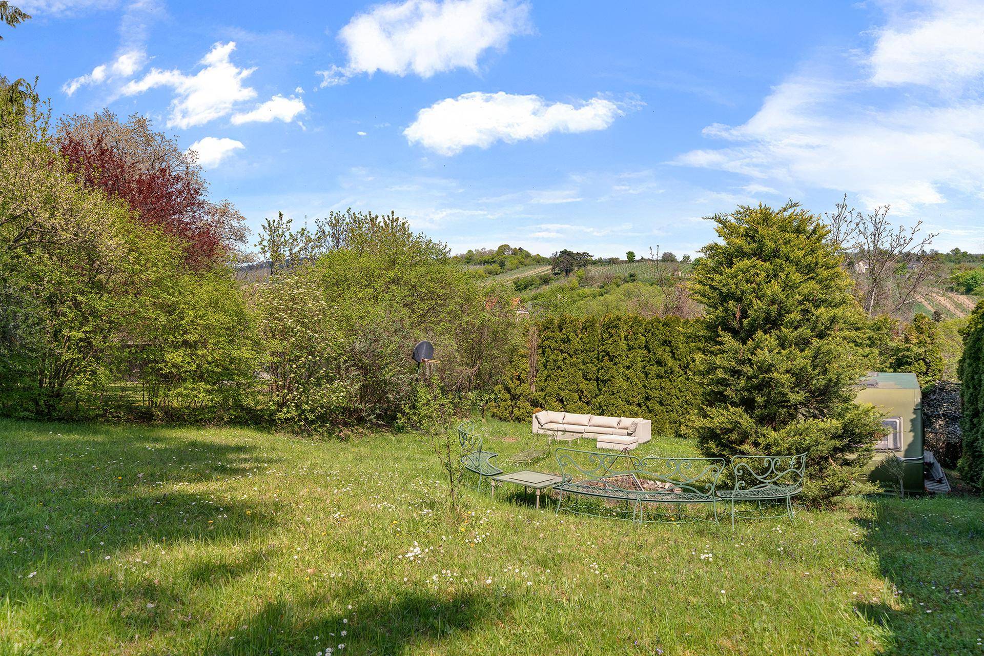 Idyllischer Gartenbereich mit Sitzgelegenheiten und weitem Blick über die umliegende Landschaft und Weinberge.