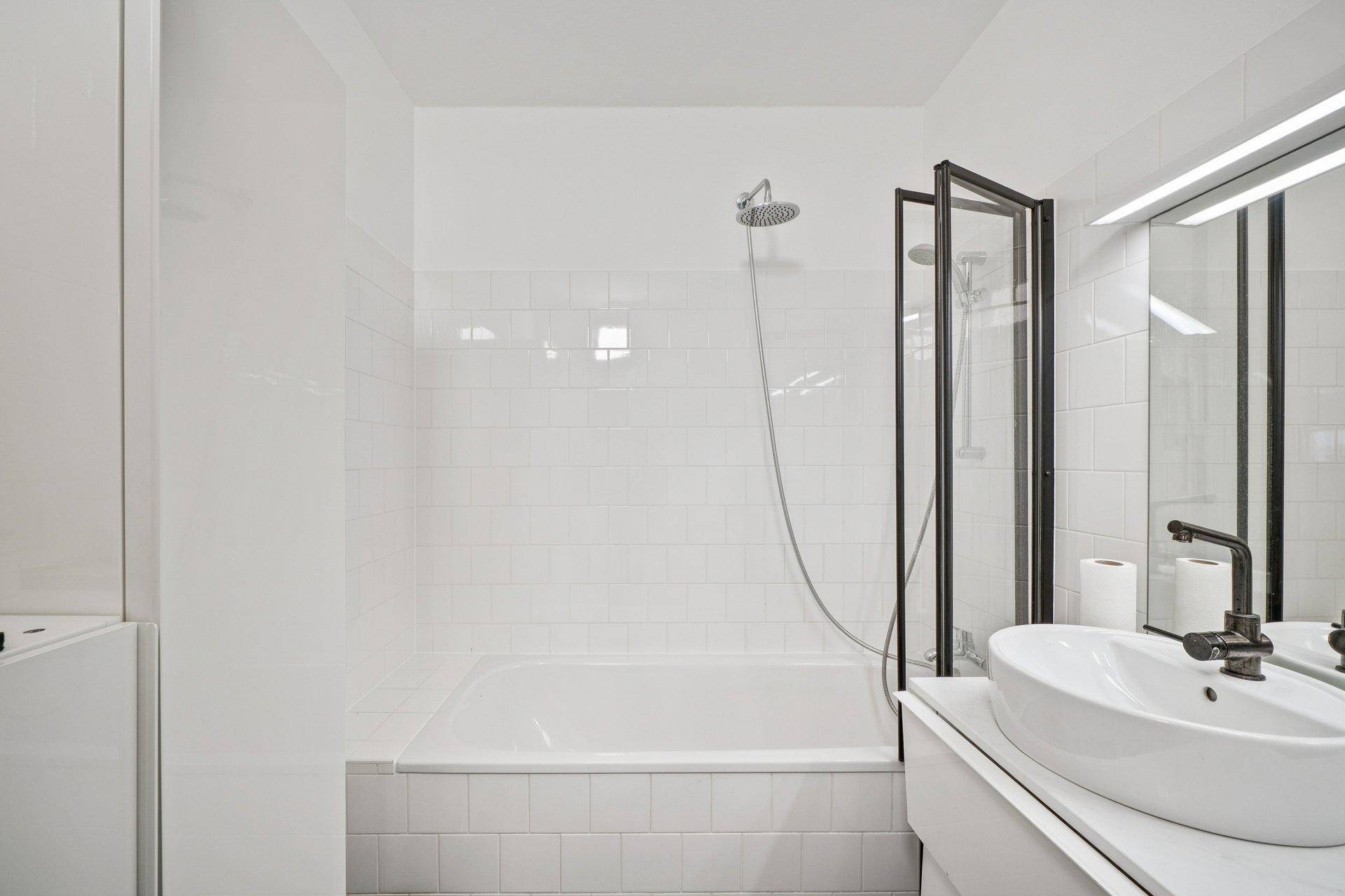 Modernes Badezimmer mit Badewanne, integrierter Dusche und elegantem Einzelwaschbecken.