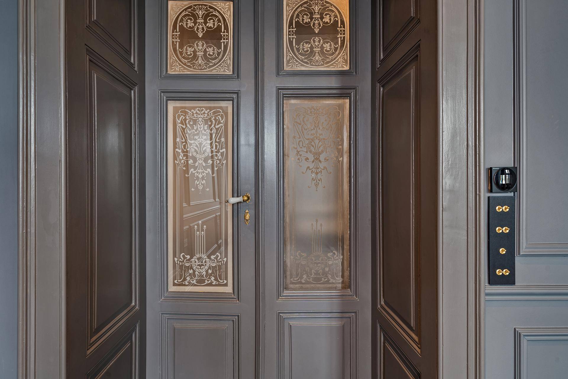 Detailaufnahme einer eleganten Eingangstür mit kunstvollen Glasverzierungen und Holzpaneelen.