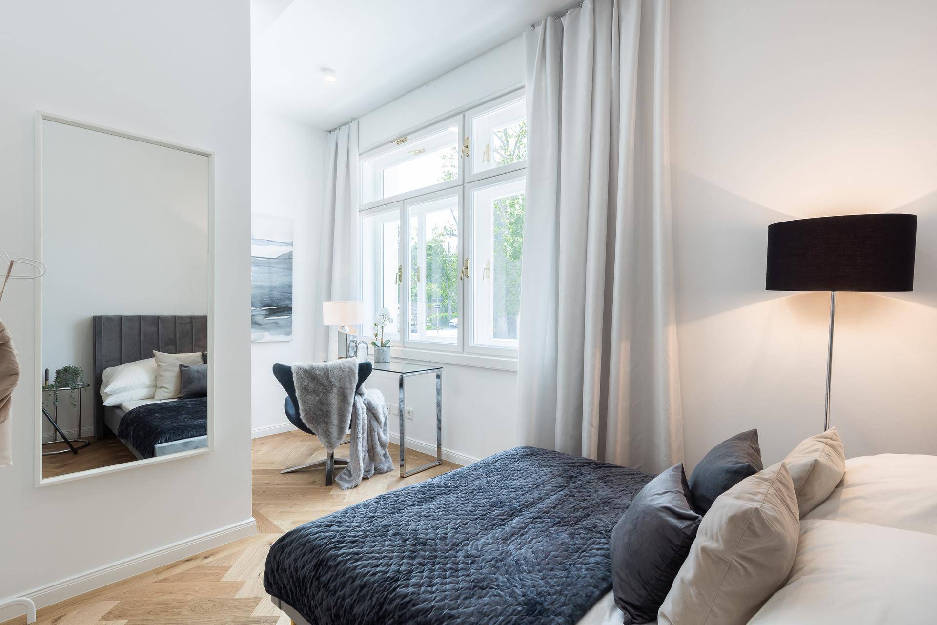 Helles Schlafzimmer mit Parkettboden, großem Fenster und modernem Interieur in ruhiger Atmosphäre.