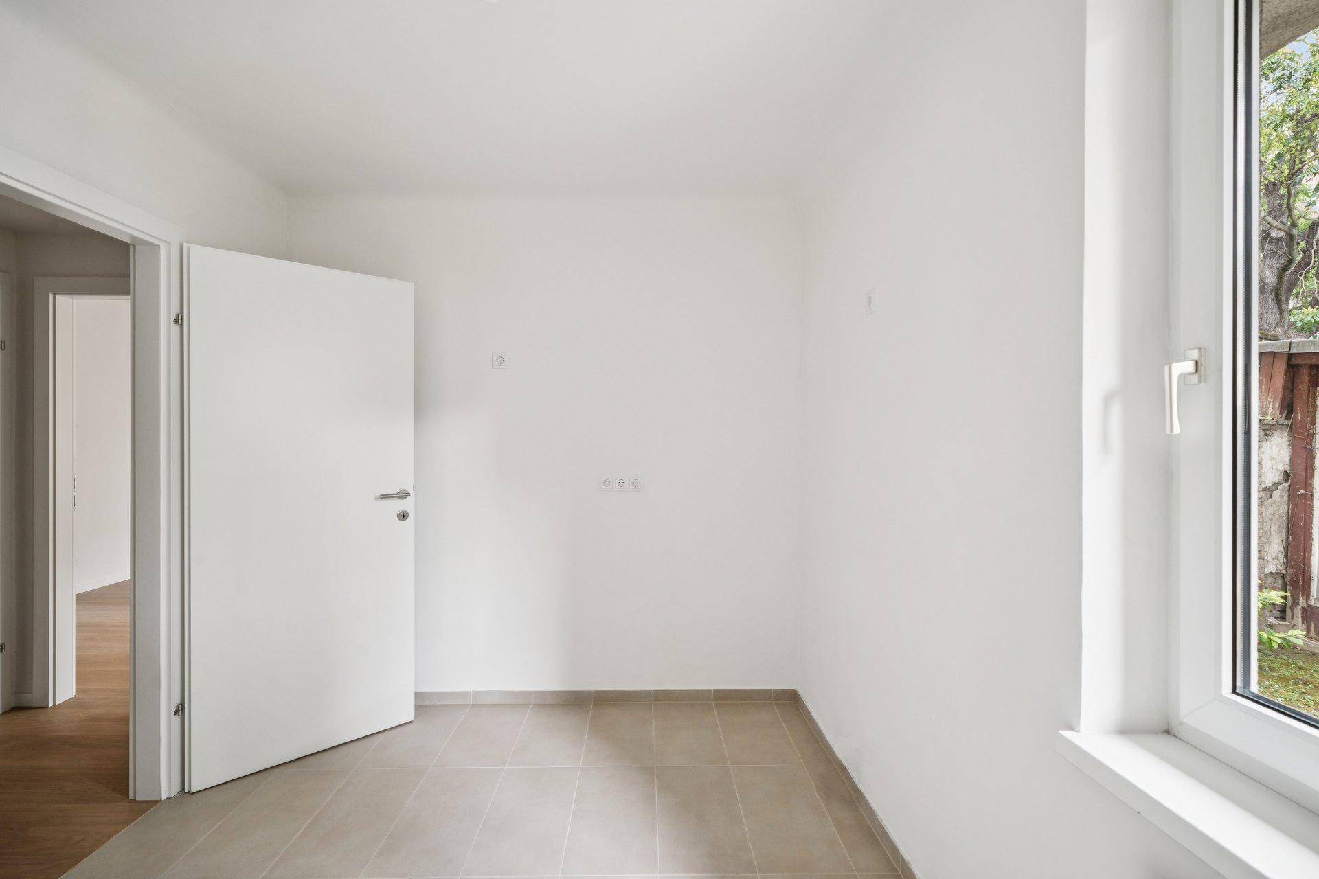 Heller Raum mit Fliesenboden und Fenster, ideal als Hauswirtschaftsraum oder Abstellkammer nutzbar.