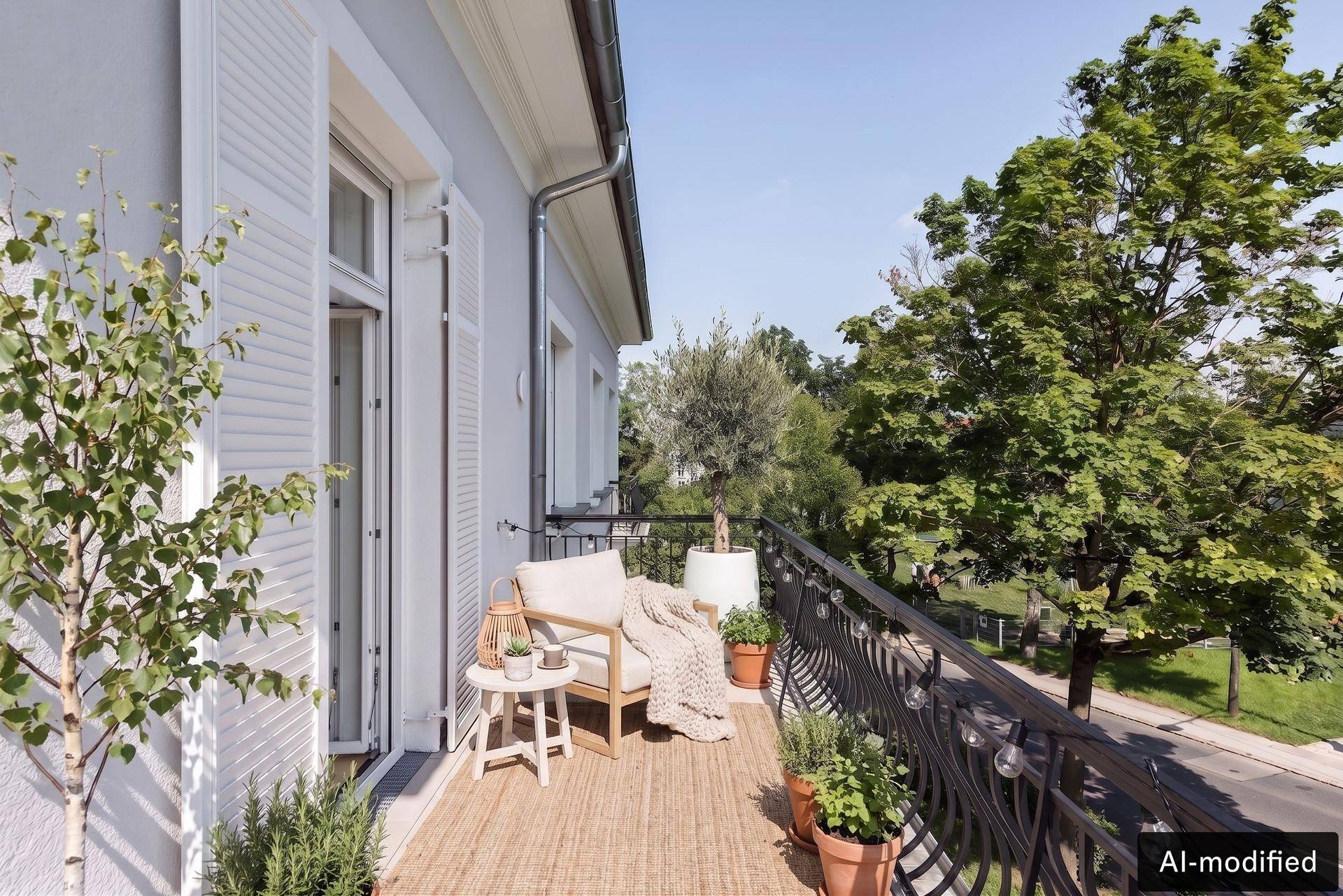 Schmaler Balkon mit Sitzgelegenheit, Pflanzen und Blick auf die umliegenden Bäume.