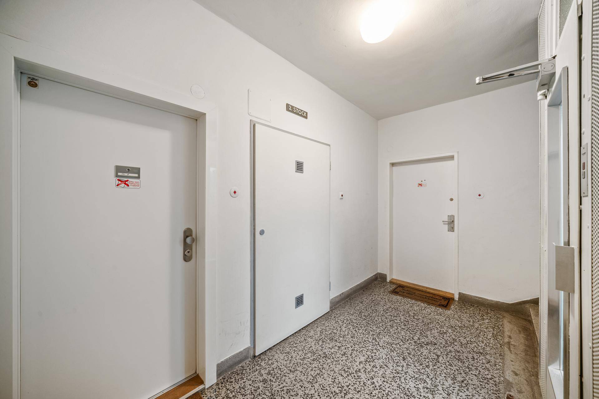 Gemeinschaftlicher Flur mit mehreren Wohnungstüren und einem robusten Terrazzoboden.