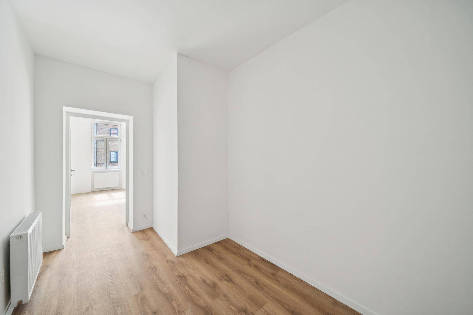 Heller Flur oder kleiner Raum mit Laminatboden und Zugang zu einem weiteren Zimmer.