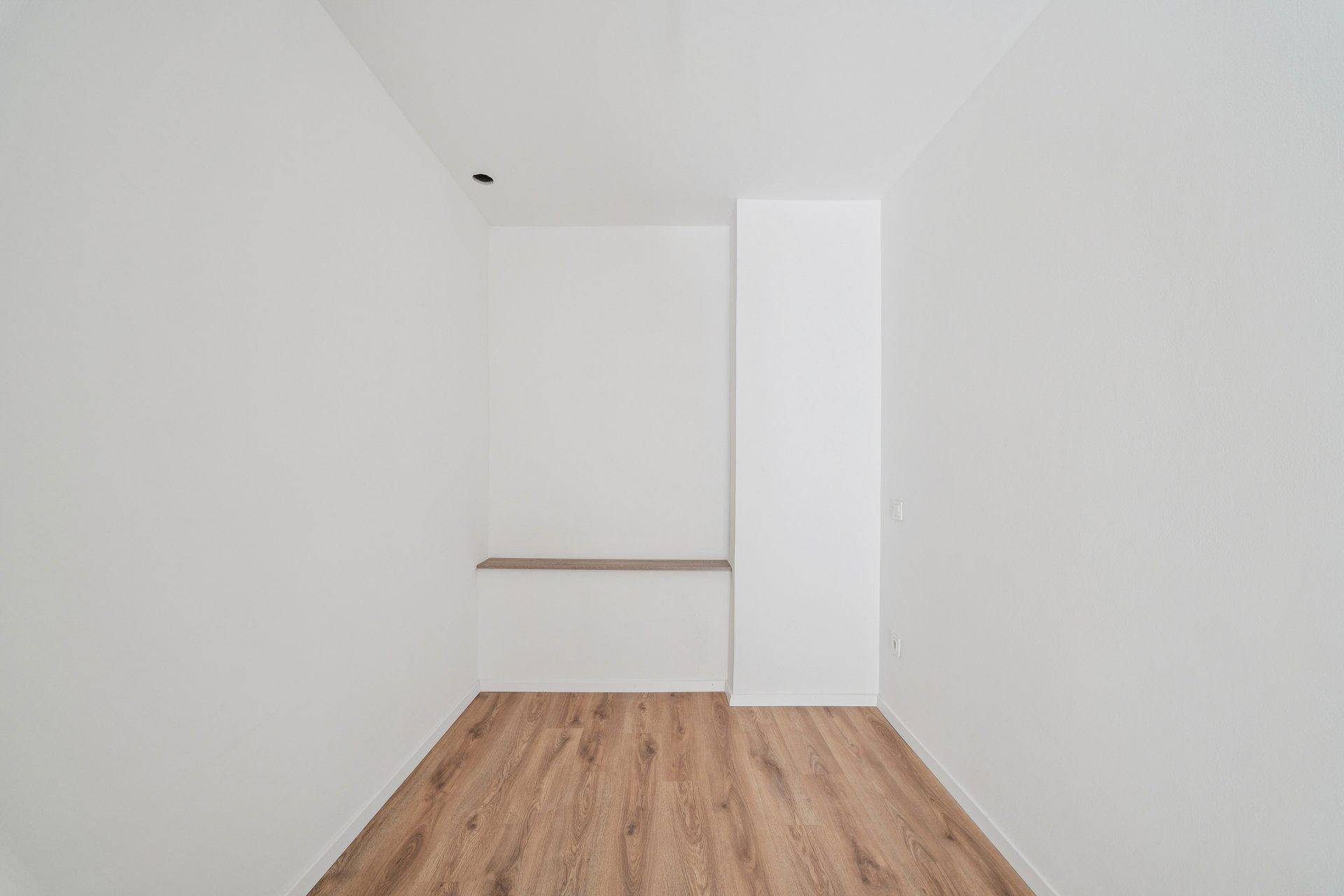 Kleiner, heller Raum mit Laminatboden und einer Ablagefläche an der Wand.