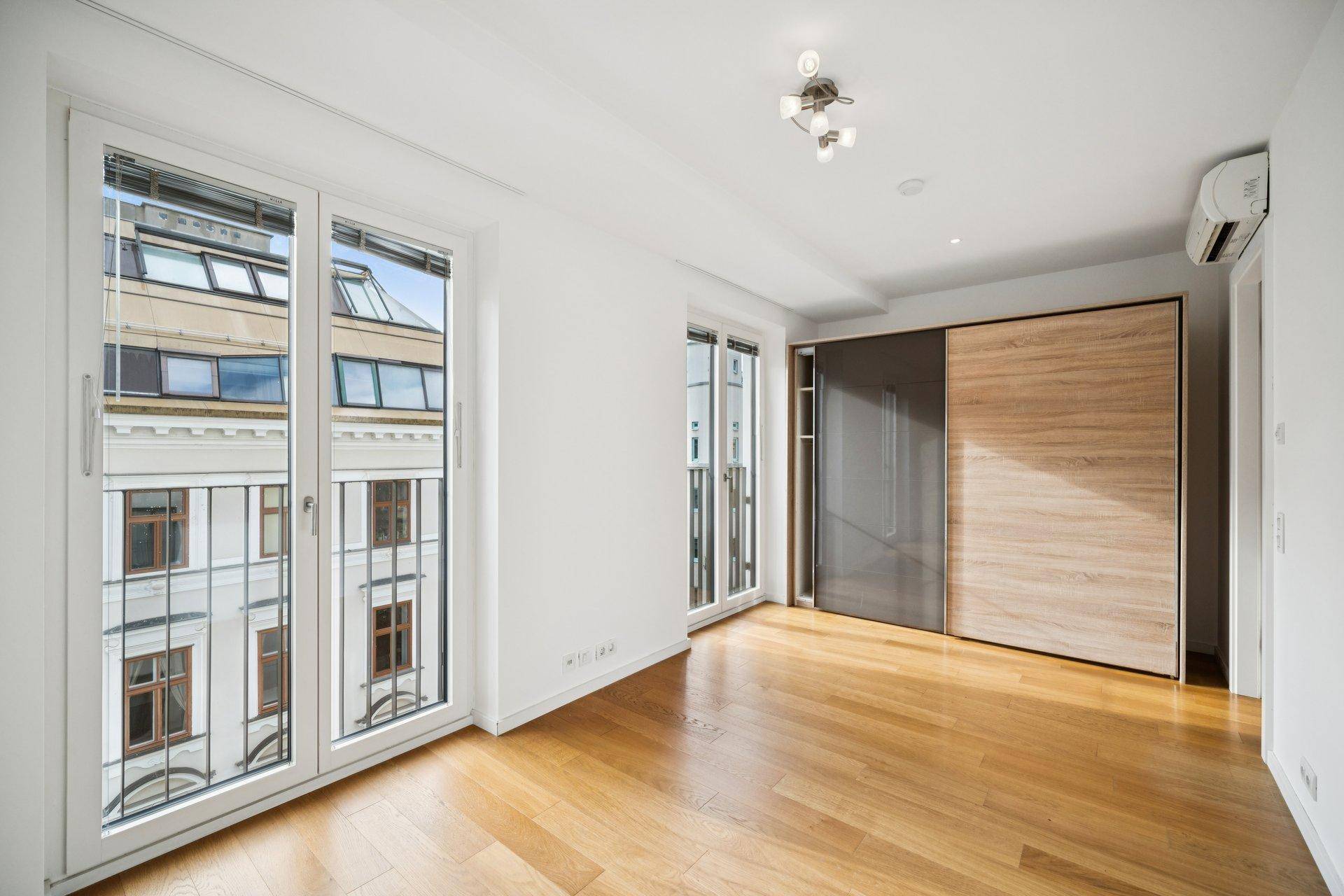 Geräumiges Schlafzimmer mit Holzboden, Einbauschrank und großen Fenstern.