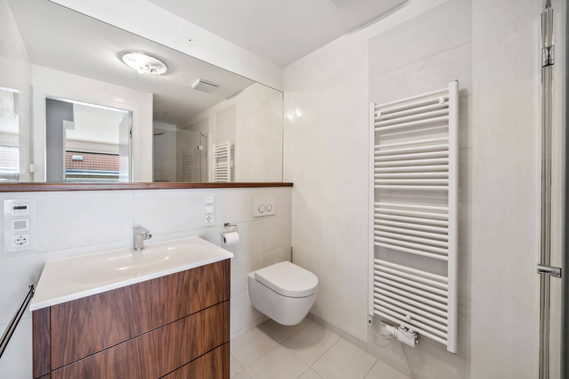 Modernes Badezimmer mit Einzelwaschbecken, Wand-WC und beheiztem Handtuchhalter.