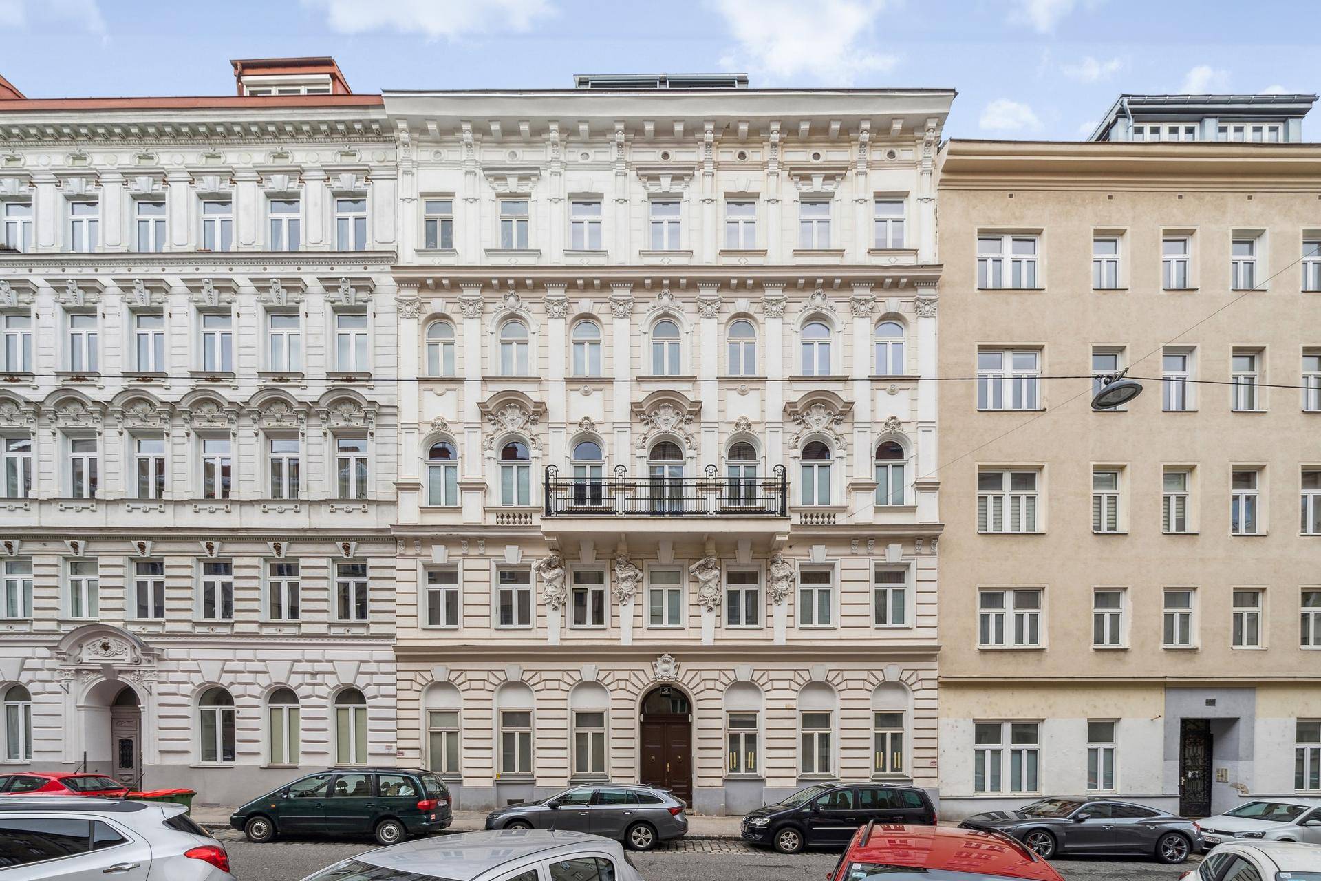 Historische Fassade eines Wiener Altbaus mit reich verzierten Fenstern und Balkon.