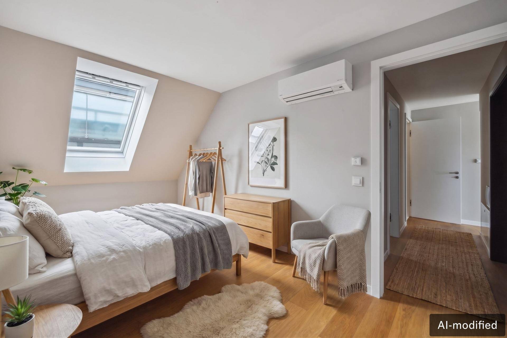 Gemütliches Schlafzimmer im Dachgeschoss mit Holzboden, Dachfenster und Klimaanlage.