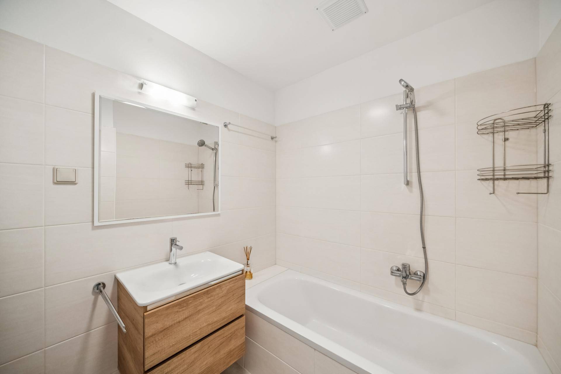 Helles Badezimmer mit Badewanne, modernem Waschtisch und hellen Fliesen.