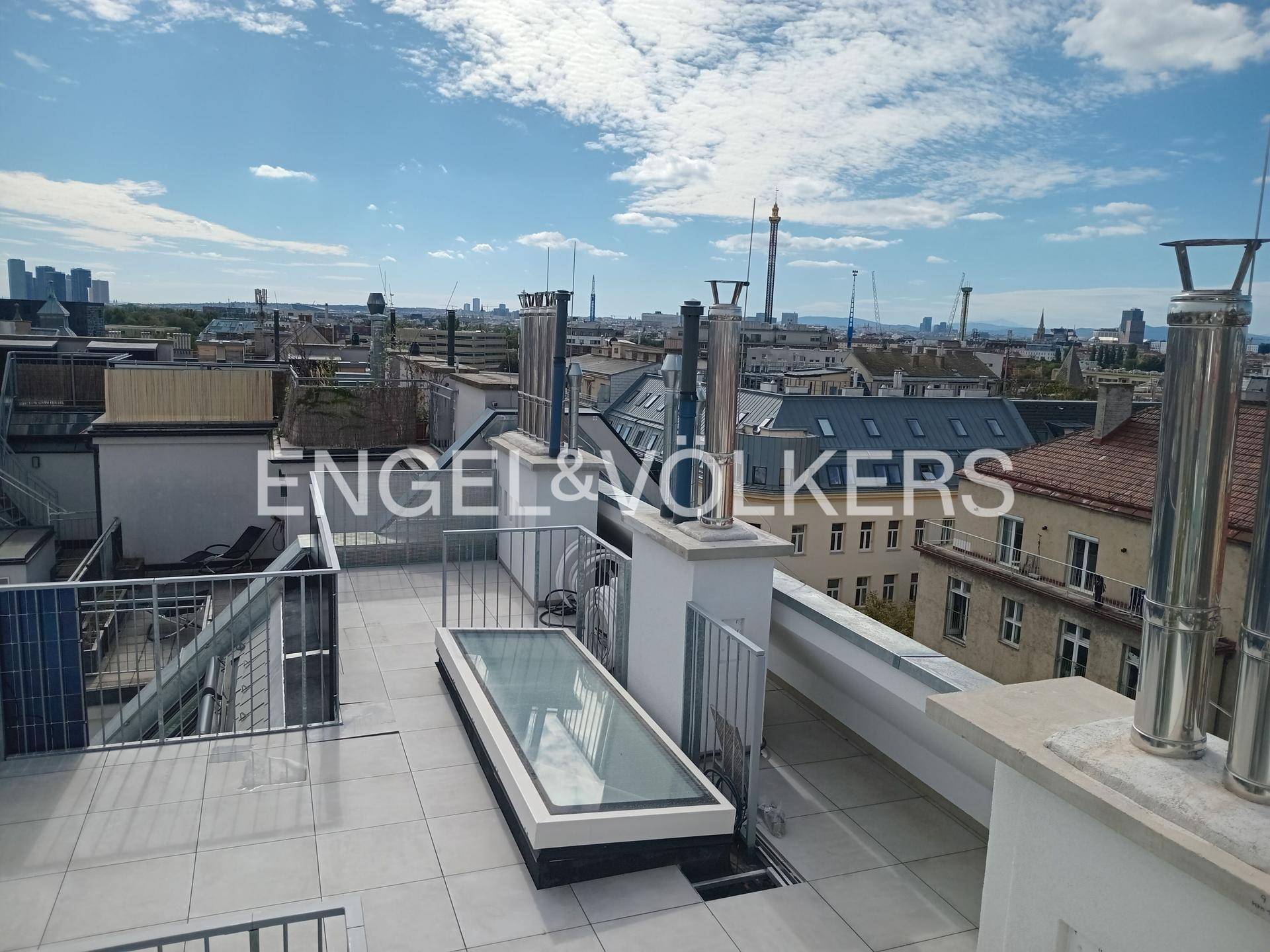 Geräumige Dachterrasse mit weitem Stadtblick und einem Oberlicht, das Licht in die darunterliegende Wohnung bringt.