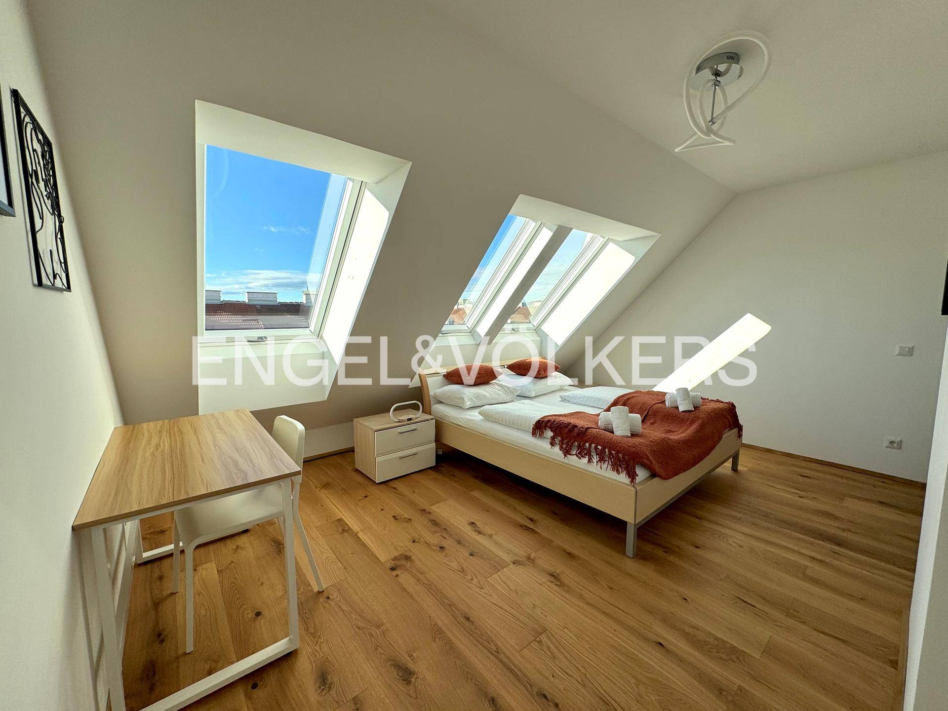 Helles Schlafzimmer mit Dachschrägen, Holzboden und großen Dachfenstern für viel Tageslicht und Ausblick.