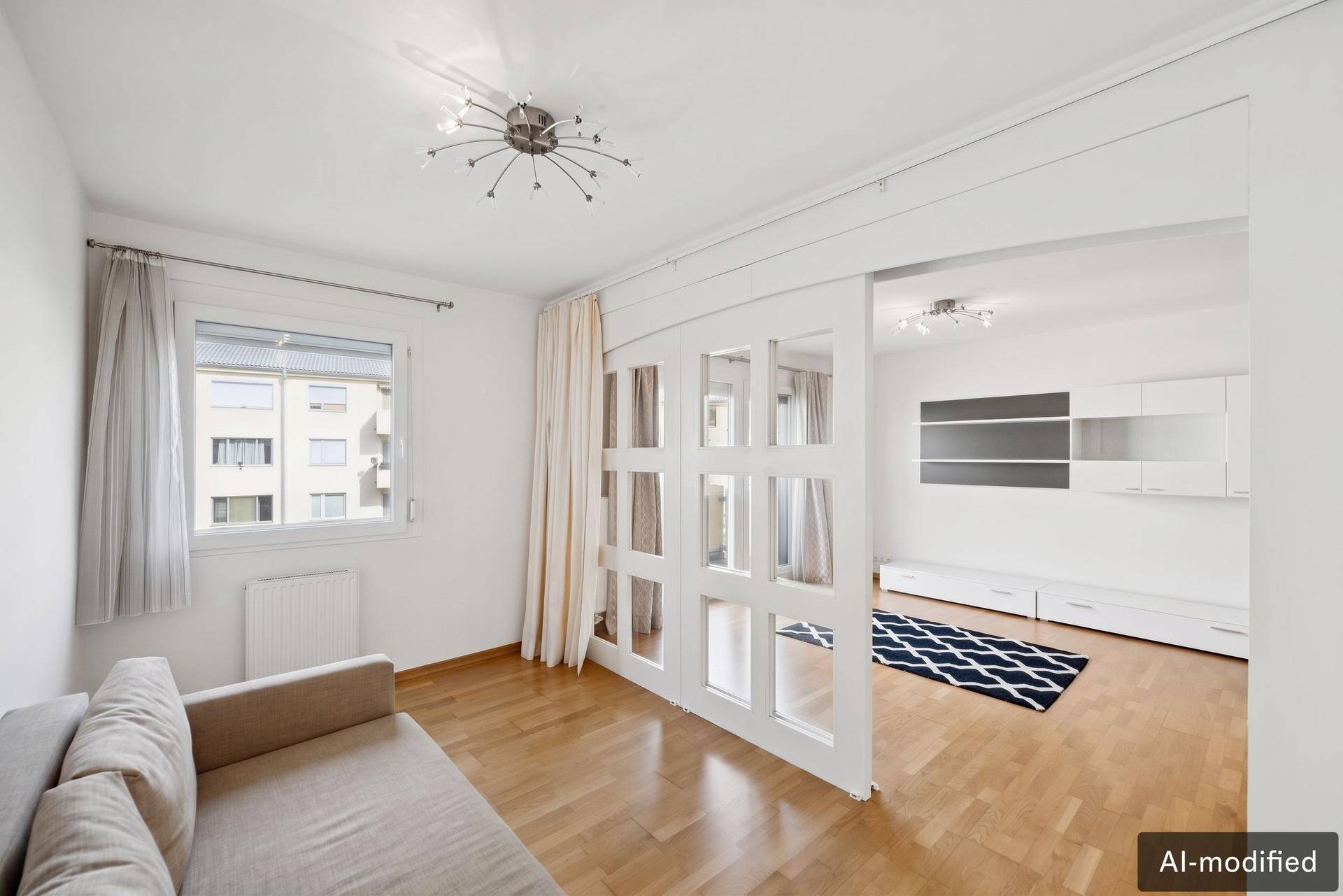 Heller Wohnbereich mit Sofa und Schiebetüren, die zu einem weiteren Zimmer führen.