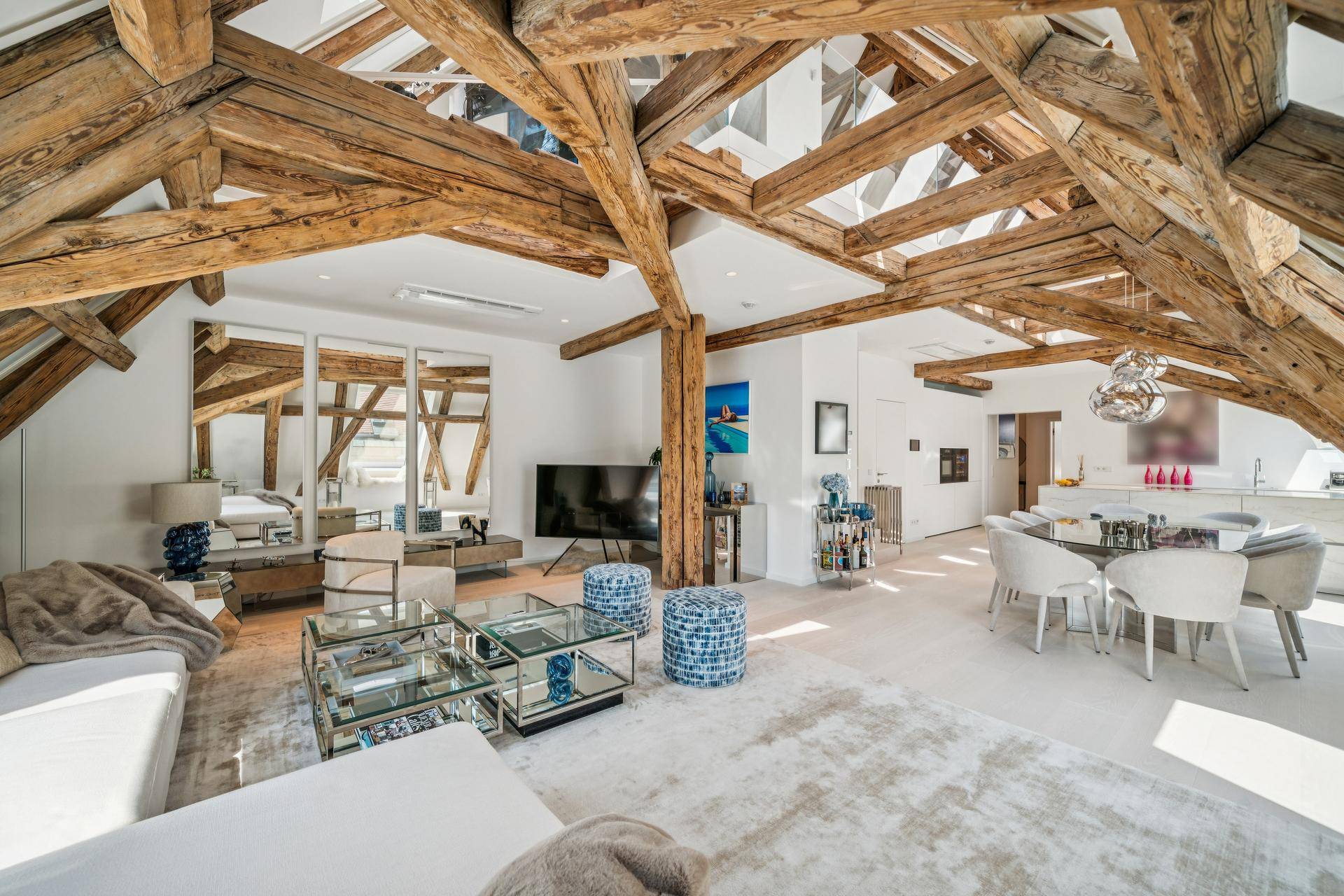 Großzügiger offener Wohnbereich mit Esszimmer und Küche, charakteristischen Holzbalken und modernen Möbeln.