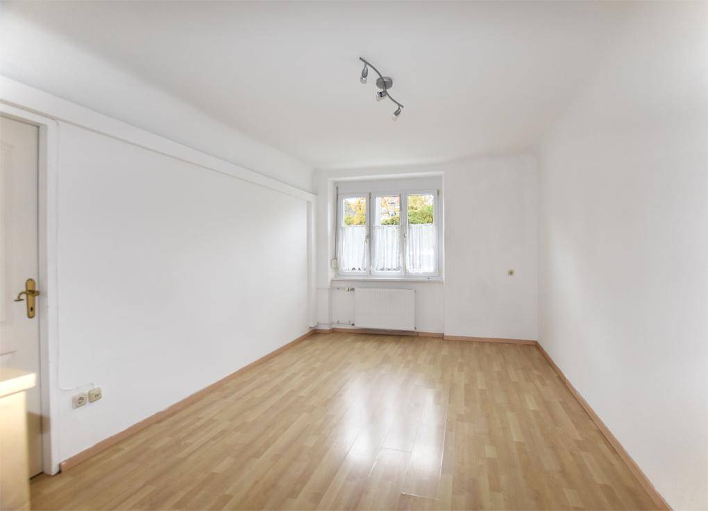 Heller Raum mit Laminatboden und einem Fenster, das für natürliche Belichtung sorgt.