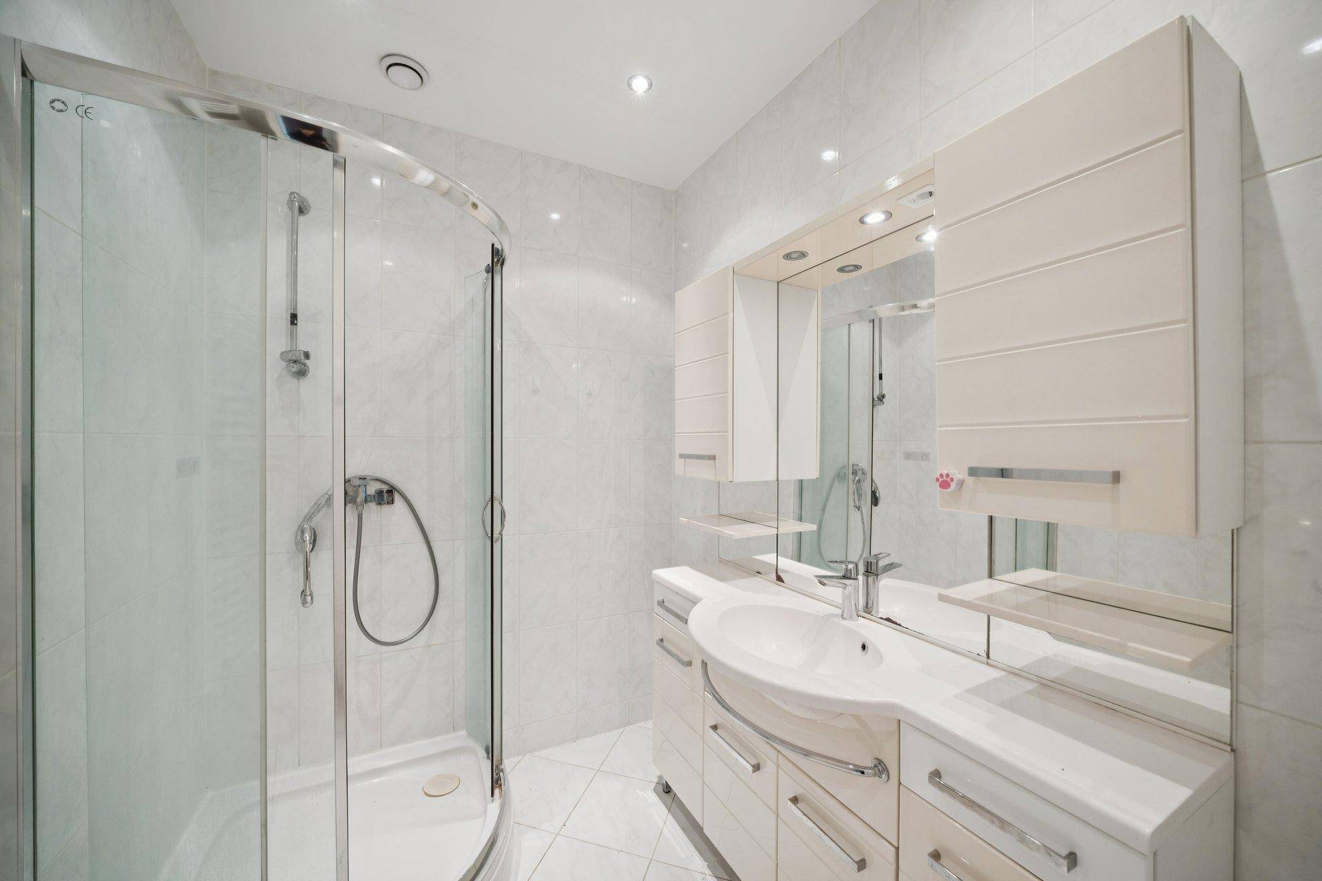 Modernes Badezimmer mit Duschkabine, Waschtisch und Spiegelschrank.
