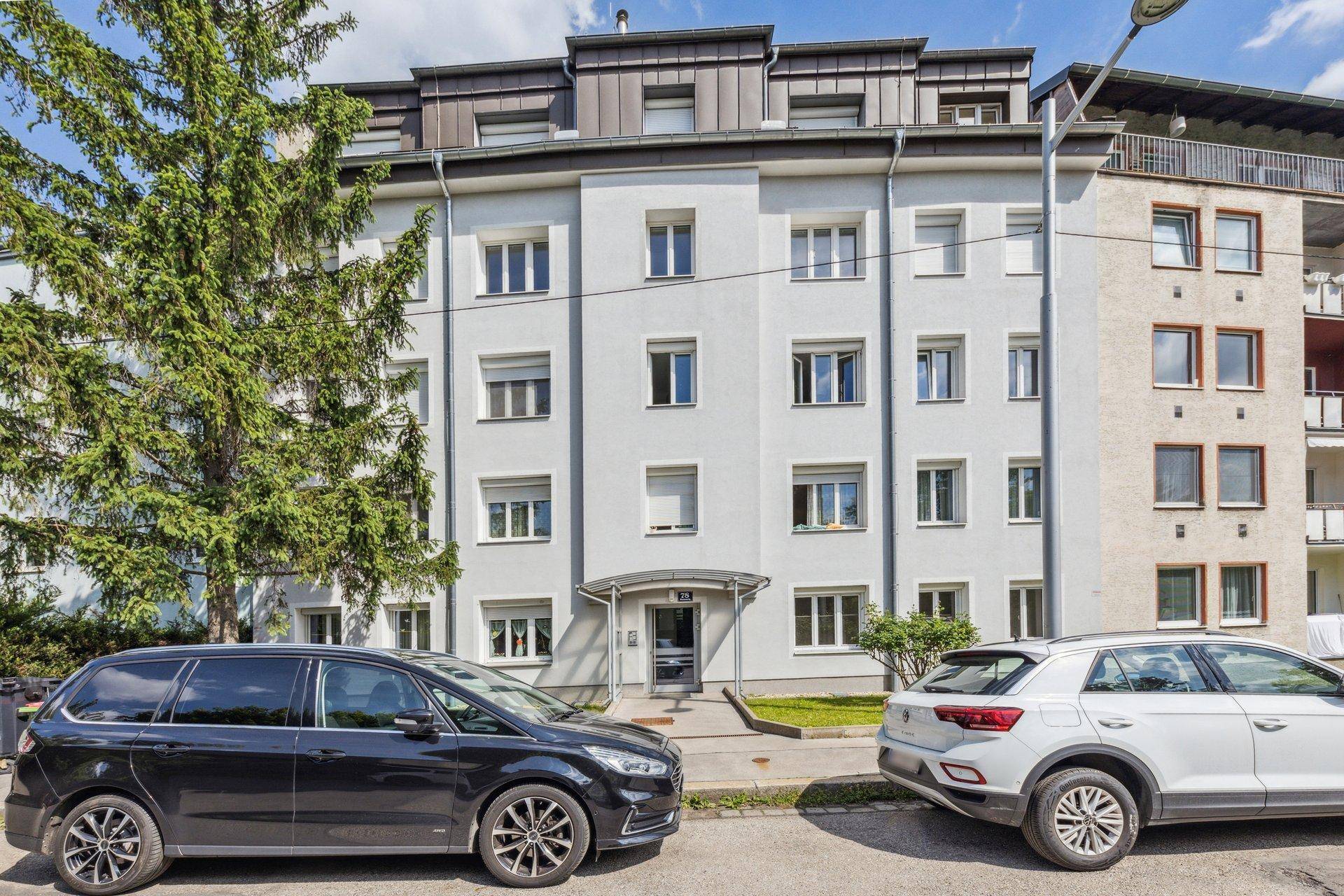 Mehrfamilienhaus mit moderner Fassade, vielen Fenstern und gepflegtem Eingangsbereich.