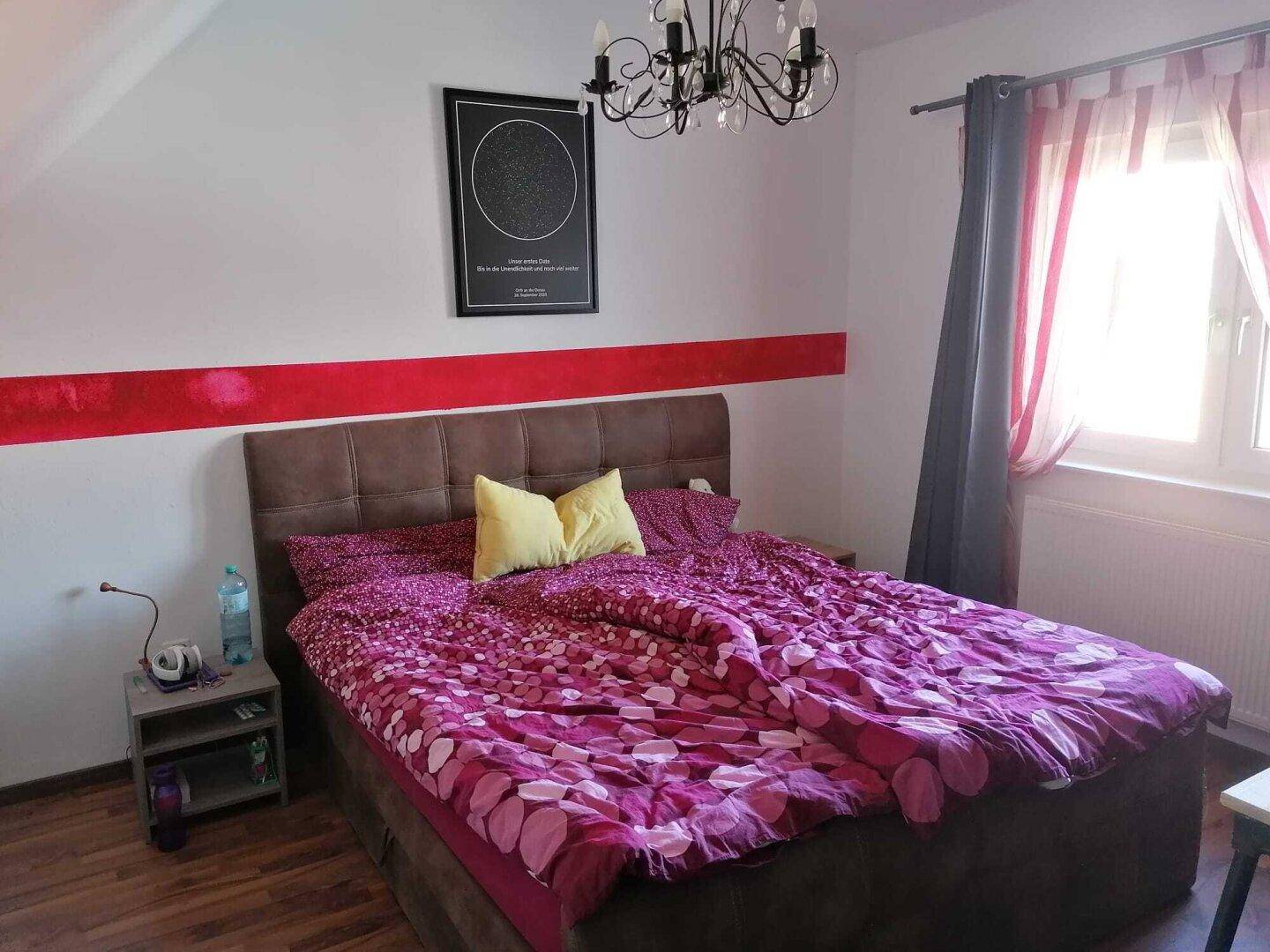 Gemütliches Schlafzimmer im Dachgeschoss mit Doppelbett und farbiger Wandgestaltung.