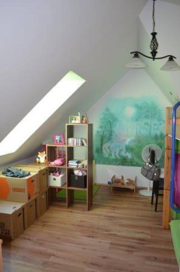 Dachzimmer mit Dachschräge, Dachfenster und Wandmalerei.