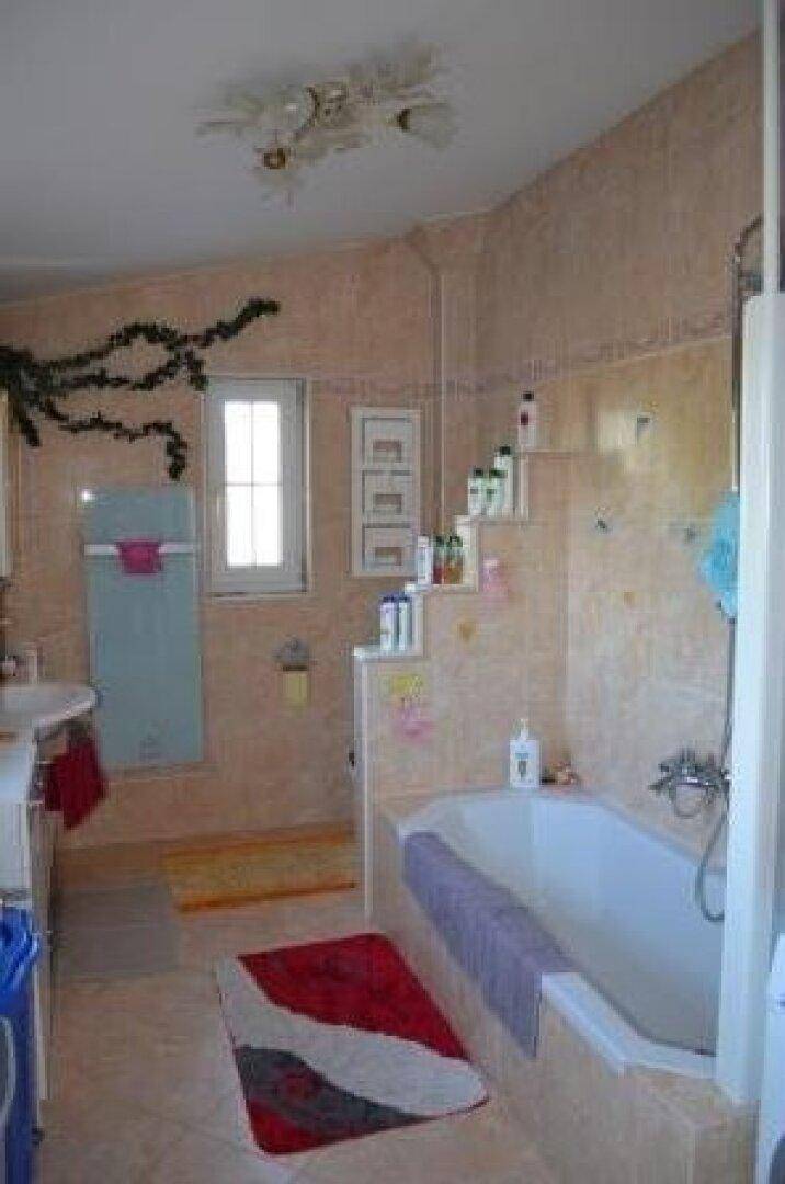 Geräumiges Badezimmer mit Badewanne, Fliesenboden und Fenster, hell und funktional.
