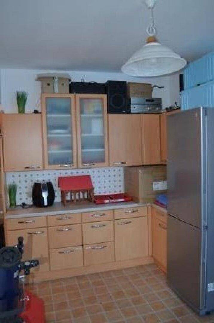 Funktionale Küche mit hellen Holzschränken, Fliesenboden und einem großen Kühlschrank für den täglichen Gebrauch.