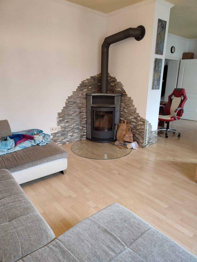 Moderner Holzofen mit Steinverkleidung als zentrales Element im Wohnzimmer.