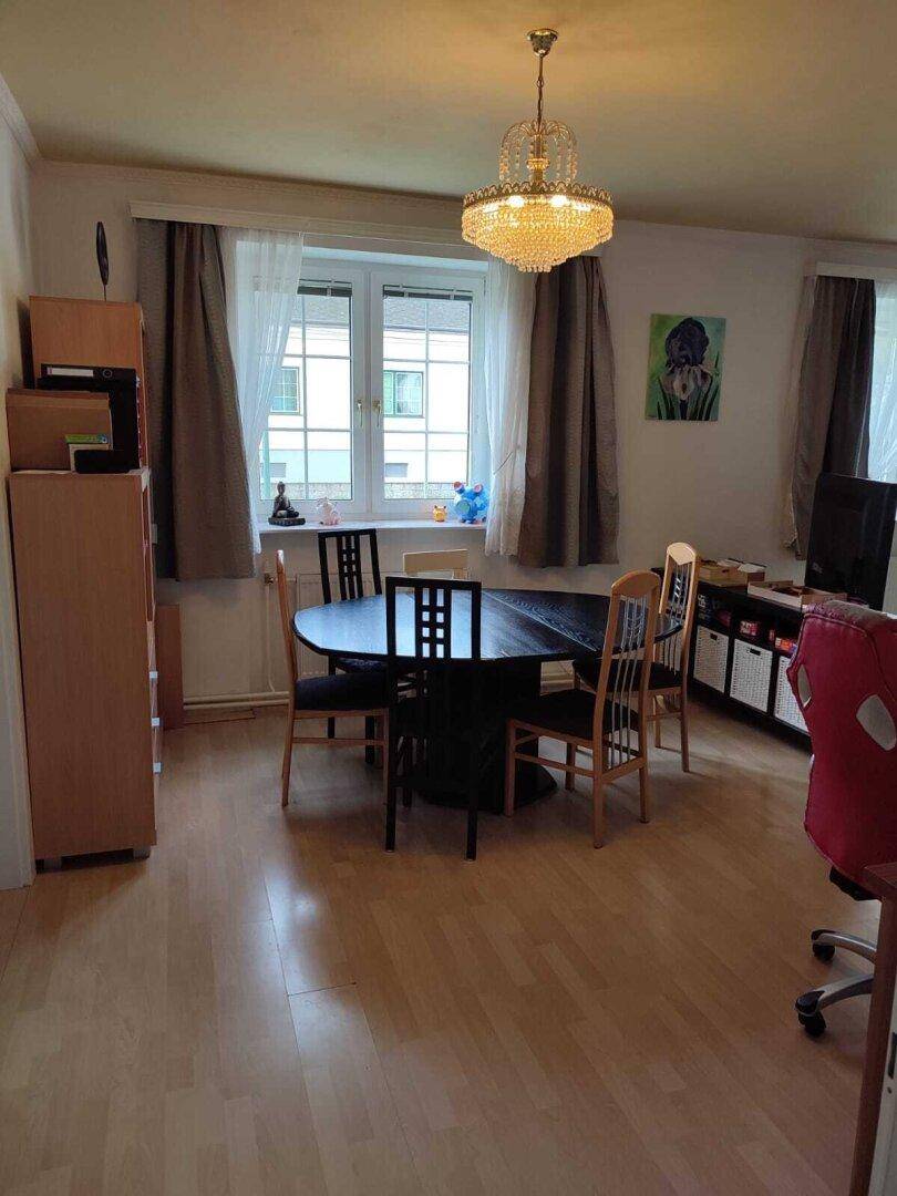 Essbereich mit dunklem Holztisch und Stühlen, angrenzend an den Wohnbereich mit Laminatboden.