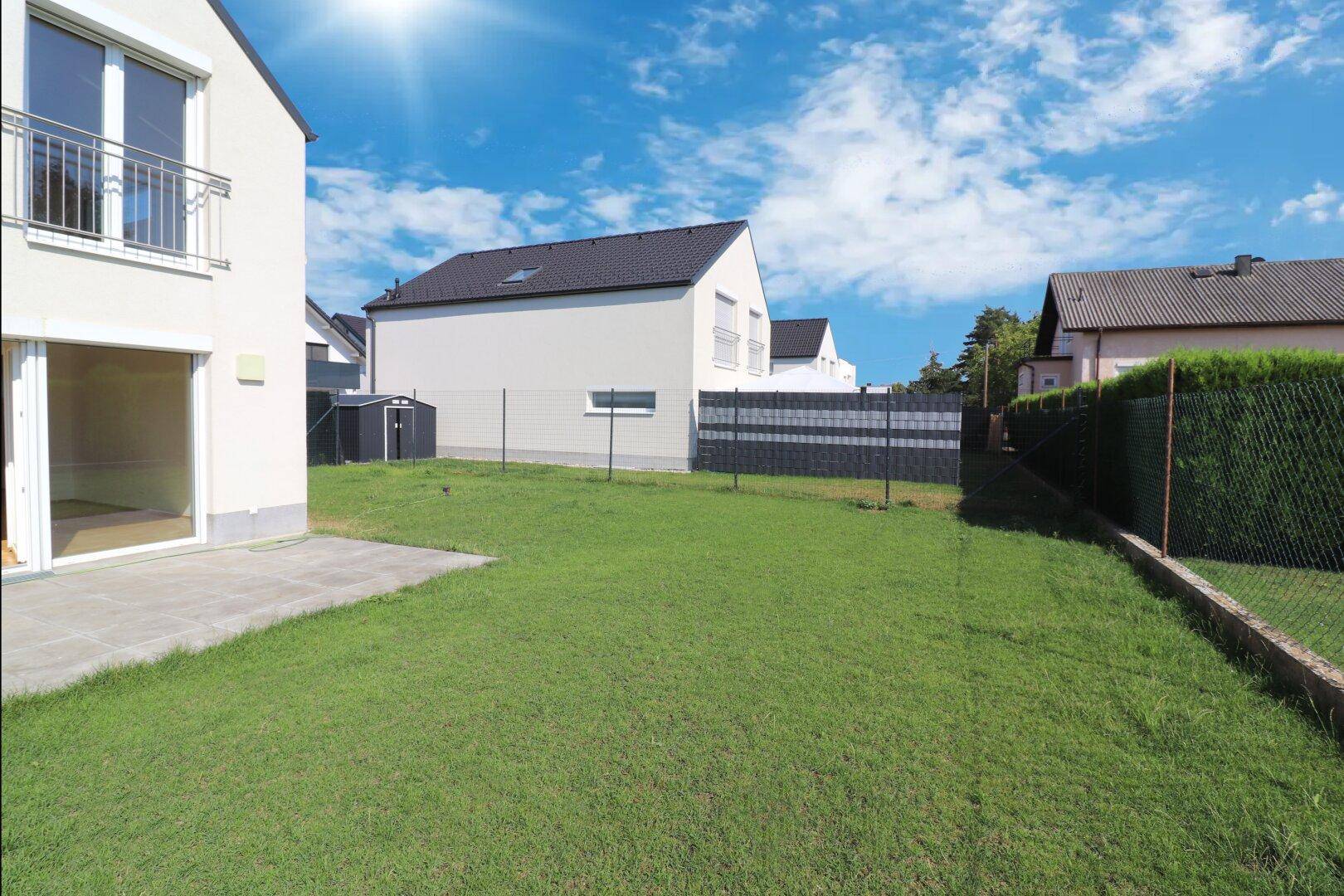 Gepflegter Gartenbereich mit Rasenfläche und Terrasse hinter dem Haus.