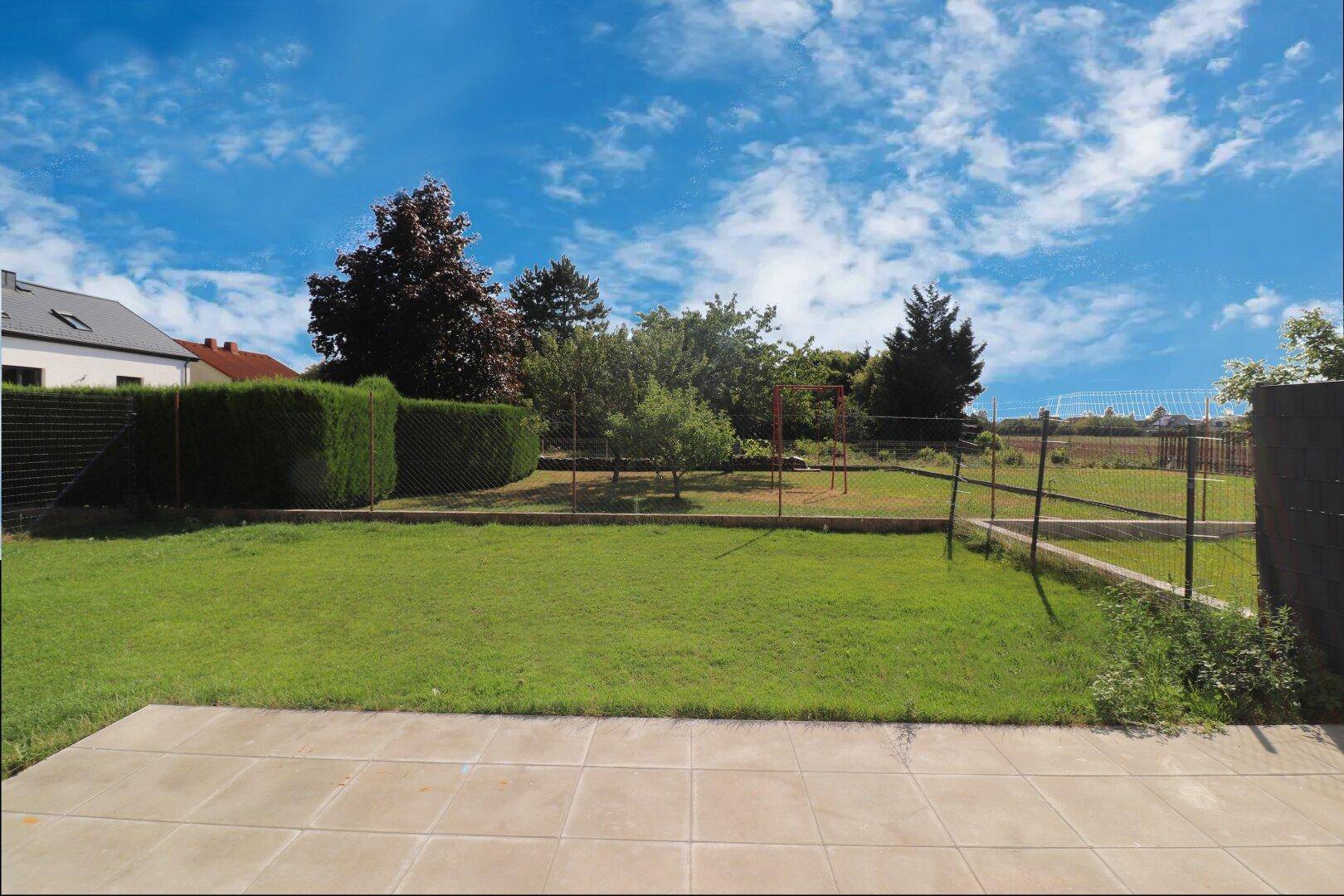 Großer Garten mit Rasenfläche, Bäumen und Blick auf die umliegende Landschaft.