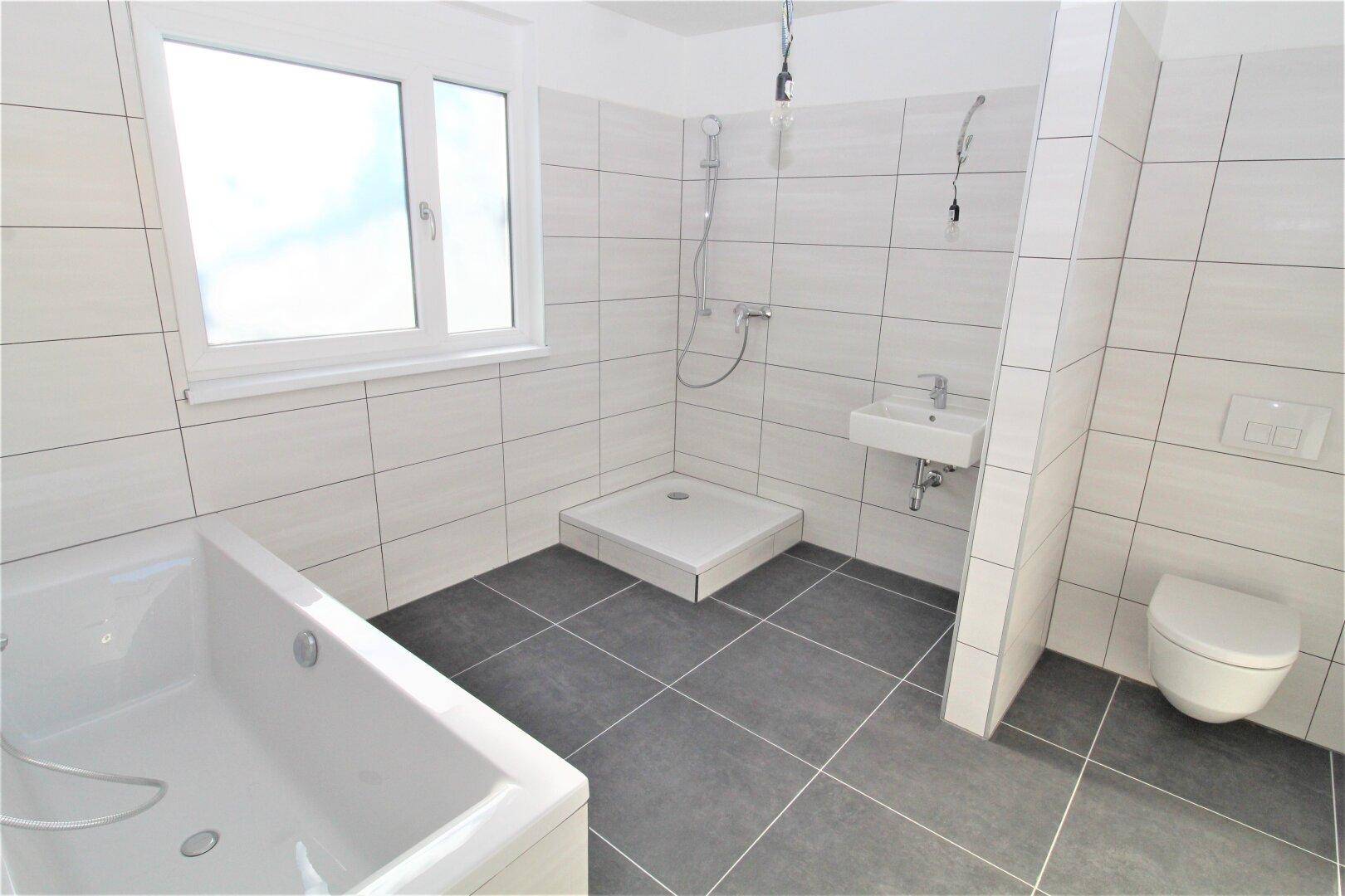 Modernes Badezimmer mit Badewanne, Dusche, WC und Fenster für natürliche Belüftung.