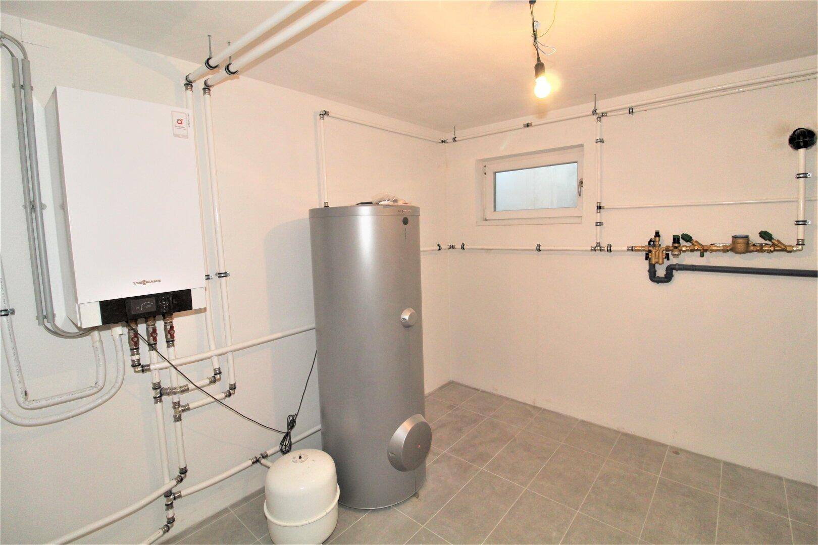 Technikraum mit Heizungsanlage und Warmwasserspeicher im Kellerbereich des Hauses.