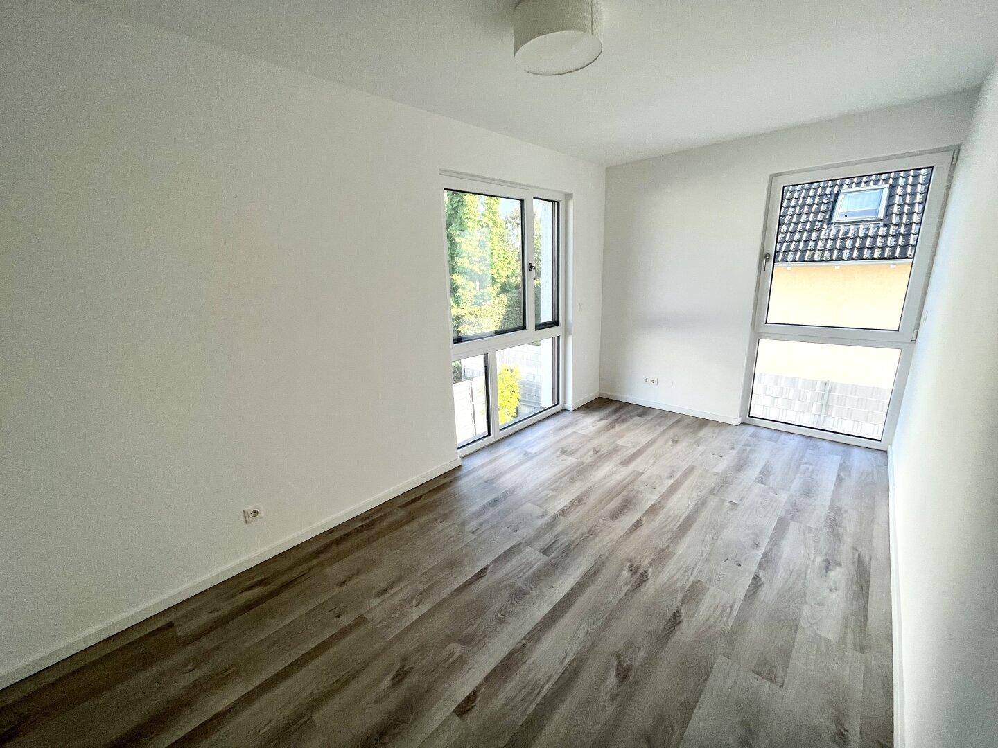 Geräumiges Schlafzimmer mit Laminatboden und mehreren Fenstern für optimale Belichtung.
