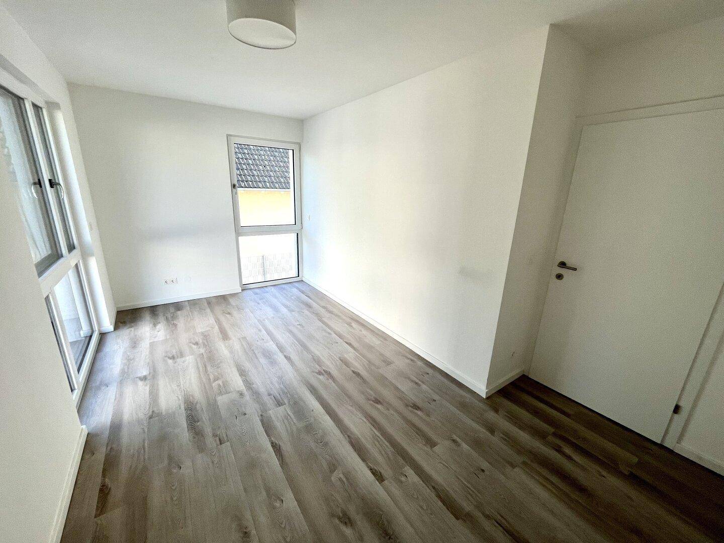 Ruhiges Schlafzimmer mit Laminatboden und Fenster, ideal für erholsame Nächte.