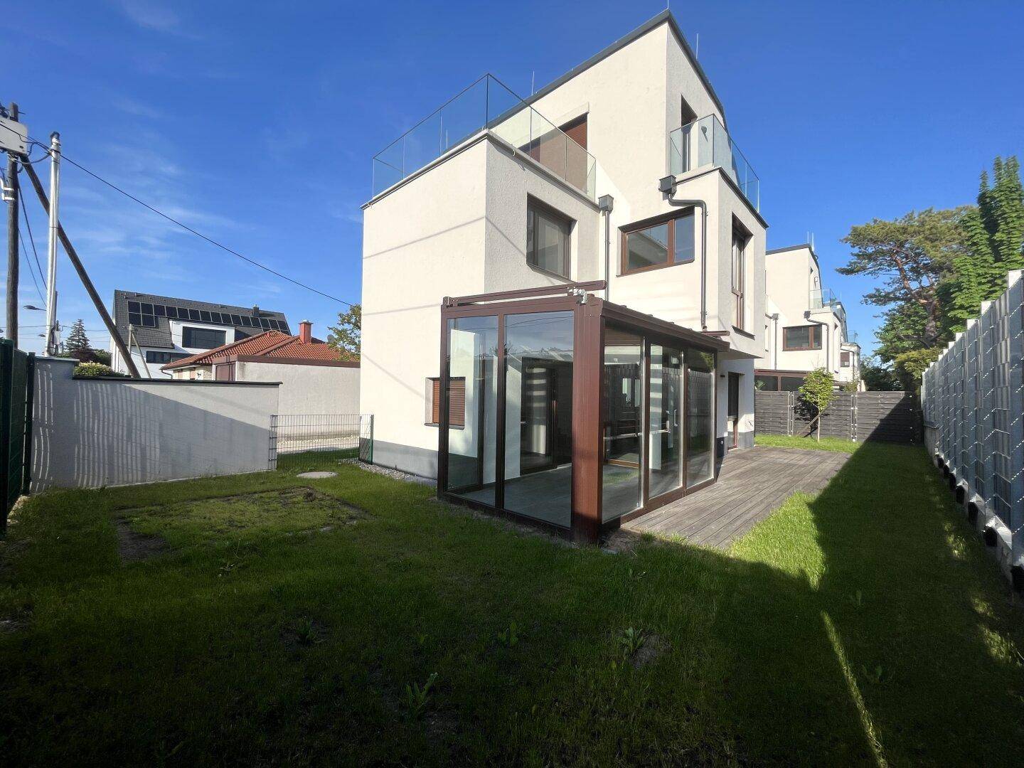 Gesamtansicht des Hauses von der Gartenseite mit Rasenfläche und Holzterrasse.