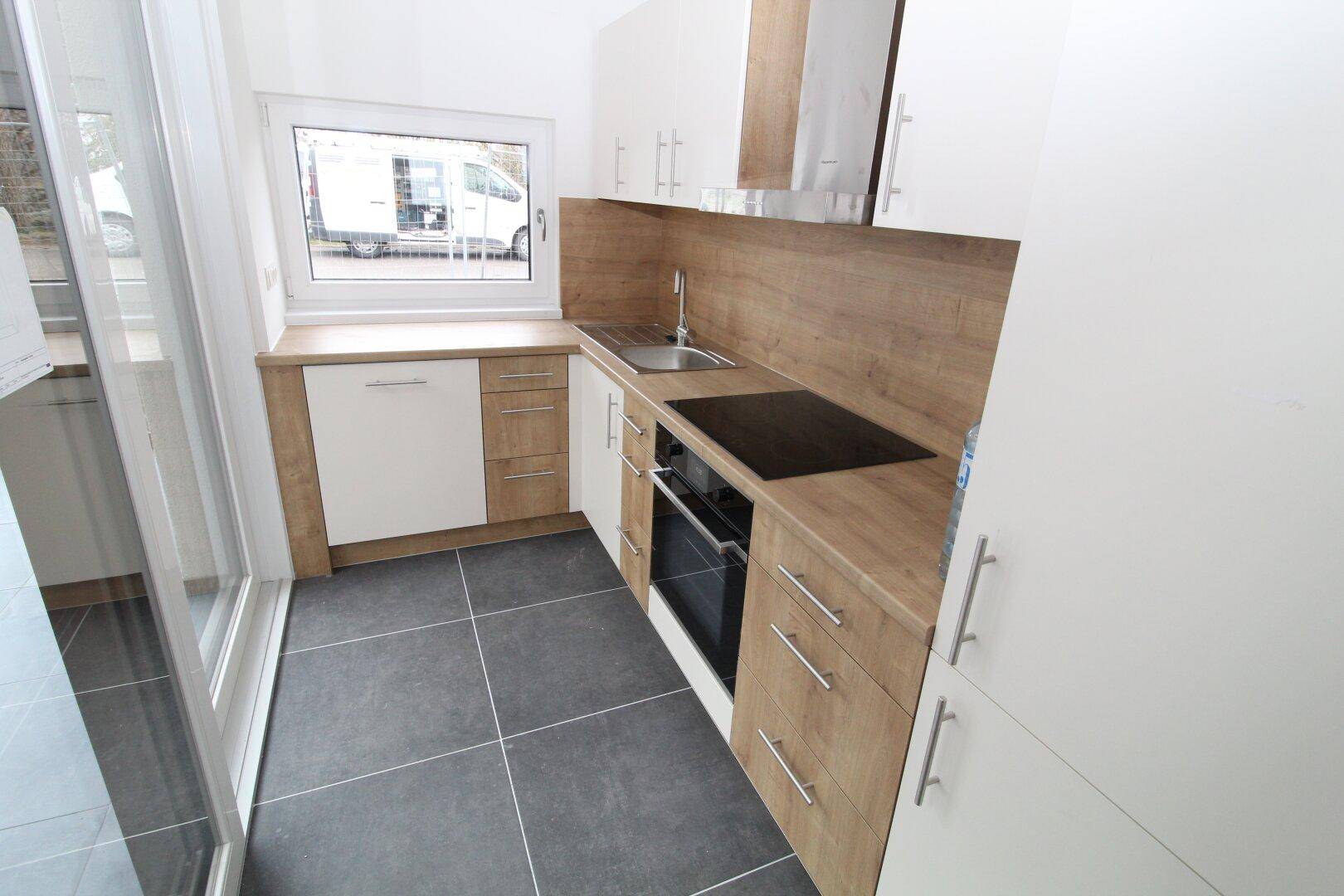 Kleine, moderne Küche mit Holz- und Weißfronten, integrierten Geräten und Fenster.