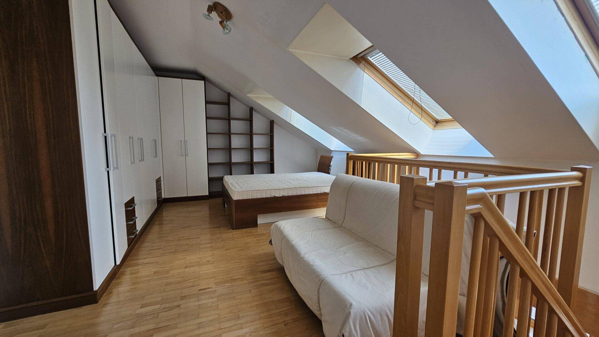 Schlafbereich im Dachgeschoss mit Dachfenstern, Holzboden und integrierten Schränken.