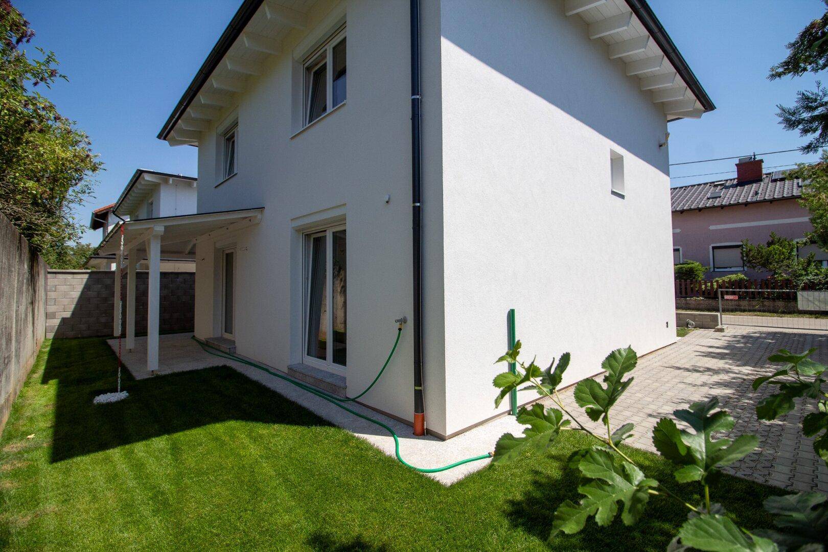 Blick vom Garten zum Haus und zu den Parkplätzen